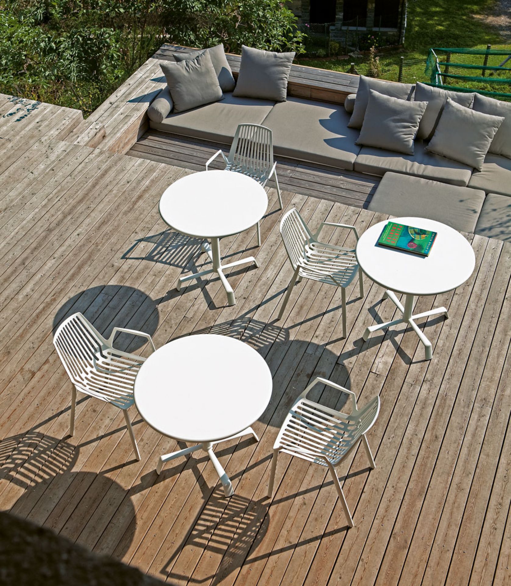 Rion Outdoor Sessel 2er-Set von Fast mit weißen Tischen auf einer Holzterrasse, Gartenmöbel für den Außenbereich.