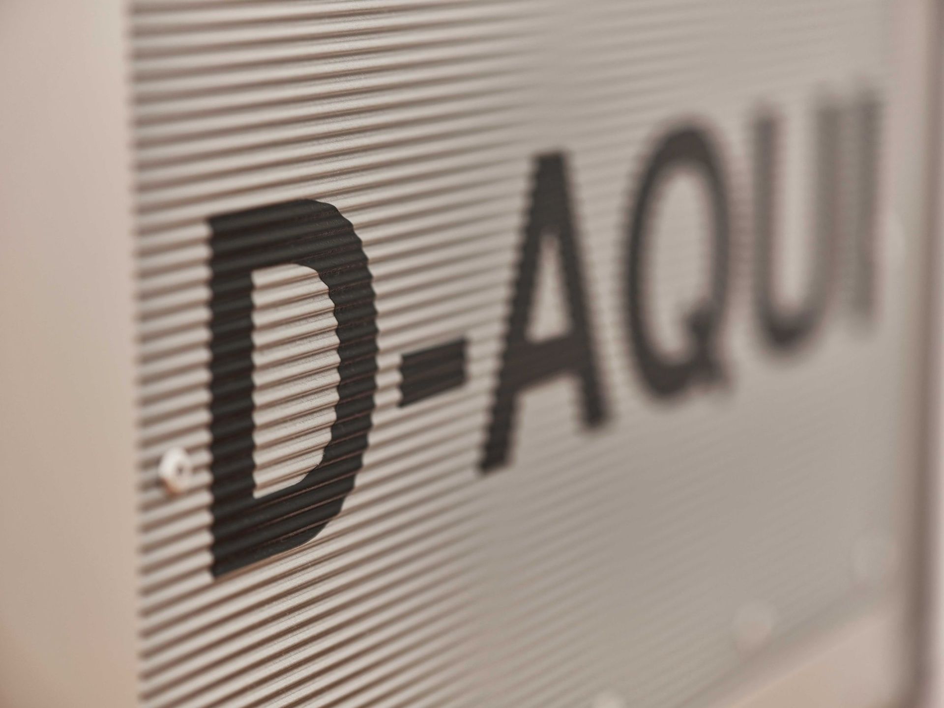 Detailaufnahme der Lufthansa Bordbar: Schriftzug "D-AQUI" auf geriffeltem Metall, ideal für Flugzeug- und Designliebhaber.
