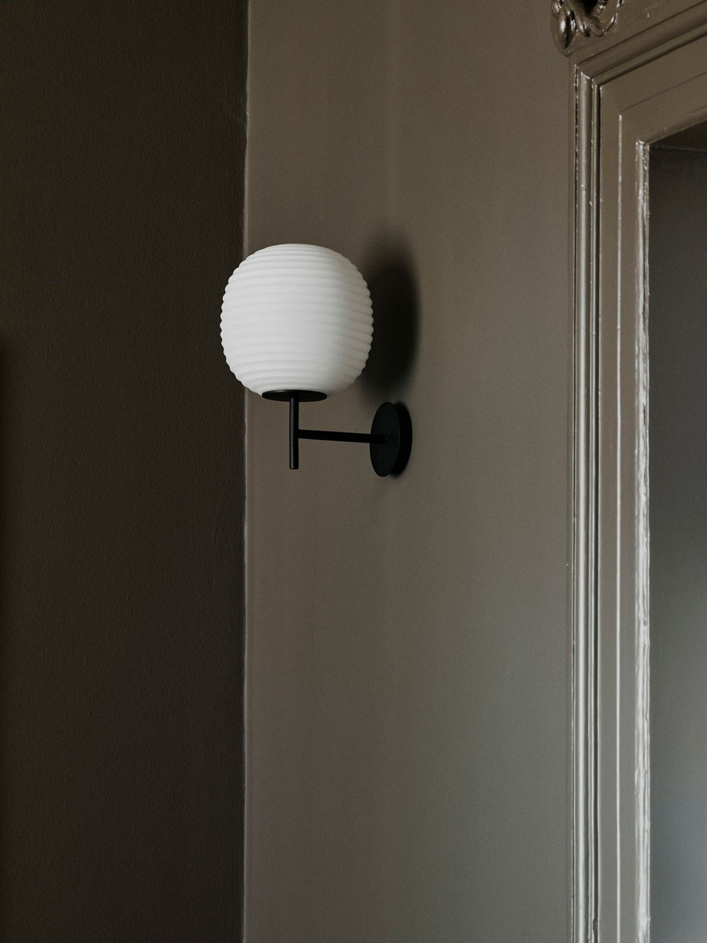 Nahaufnahme der New Works Lantern Wandleuchte small mit weißem Schirm und schwarzer Halterung.