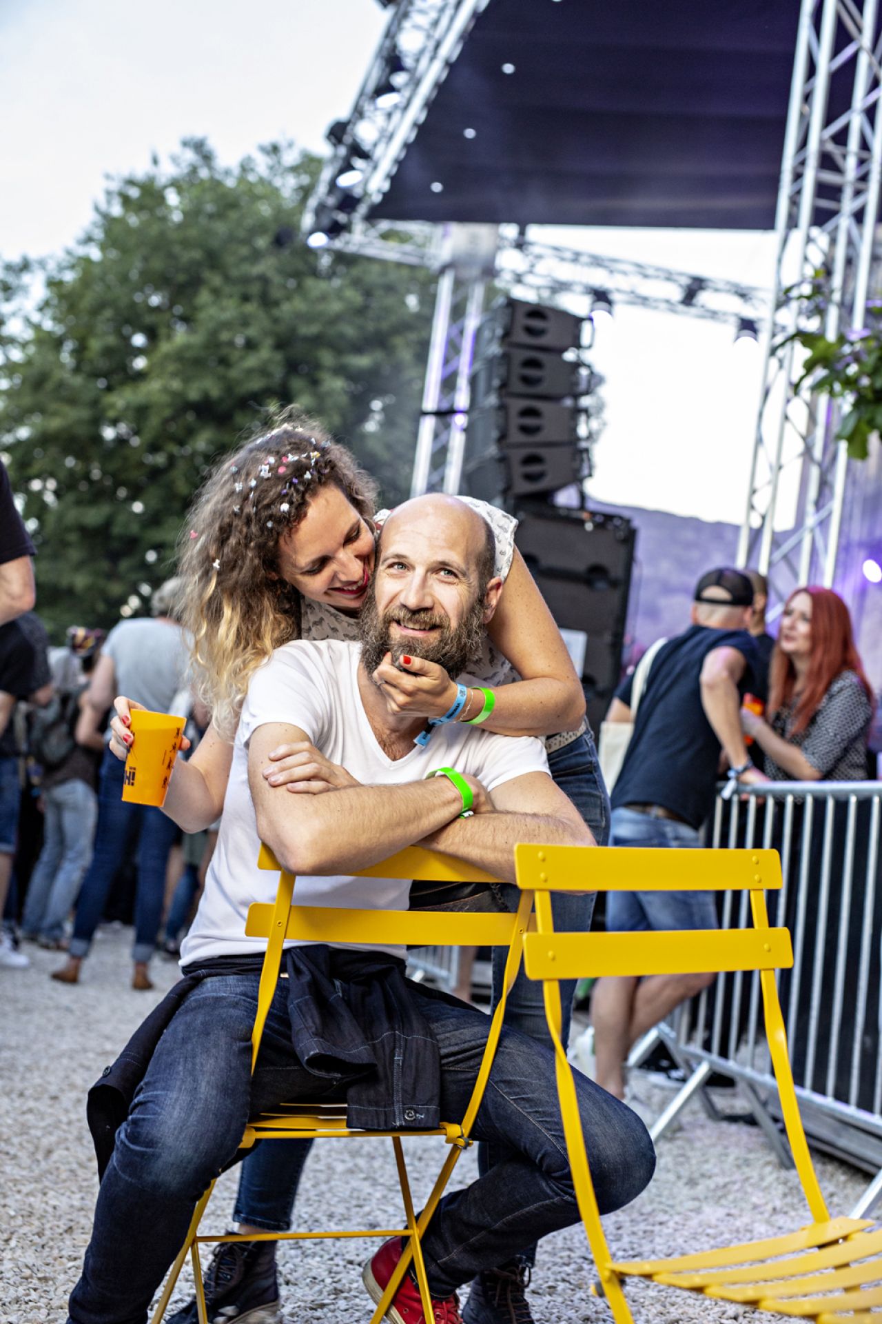Gelber Bistro Outdoor Metallstuhl von Fermob: Mann sitzt entspannt auf dem Gartenstuhl, Frau umarmt ihn liebevoll.