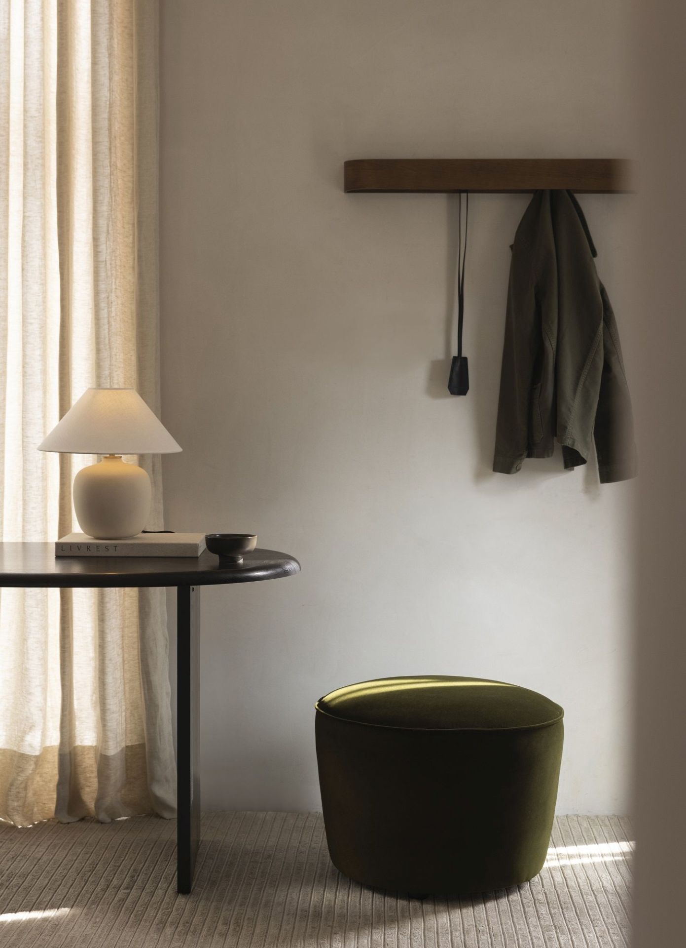 Nahaufnahme des Audo Copenhagen Eclipse Desk Schreibtischs mit Lampe, Buch und grünem Hocker in minimalistischem Interieur.