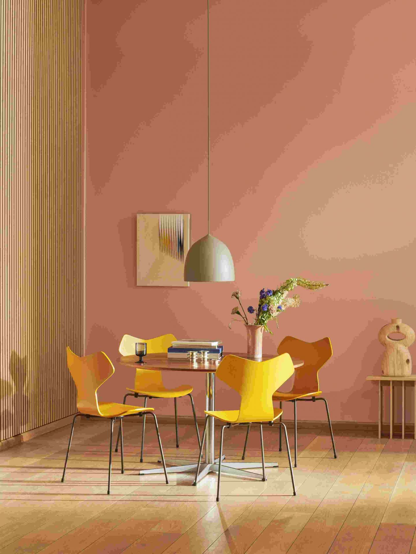Gelbe Fritz Hansen Grand Prix Stühle um einen runden Esstisch in einem modern eingerichteten Esszimmer.