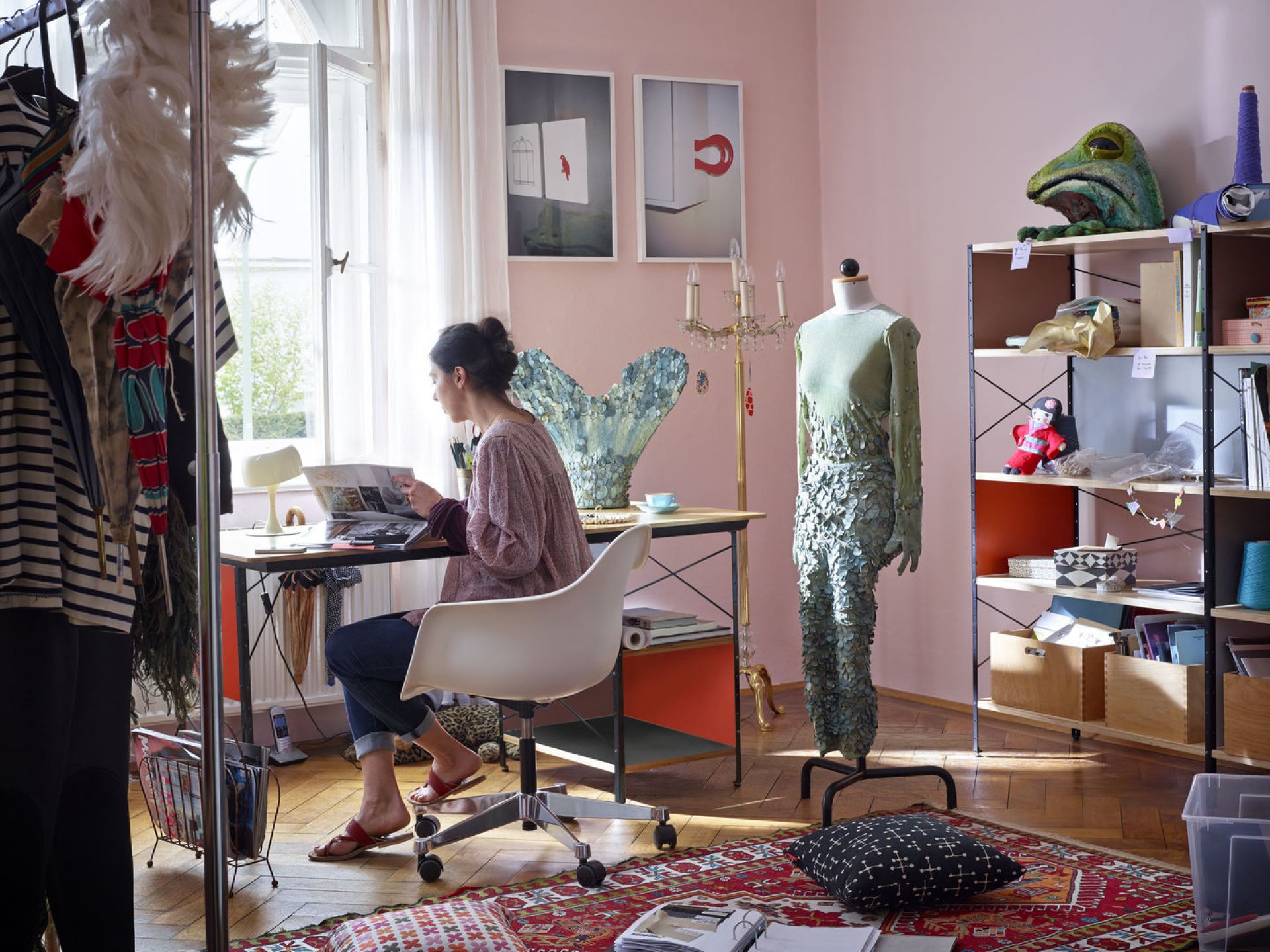 Frau sitzt an Schreibtisch auf einem weißen Eames Plastic Arm Chair von Vitra.