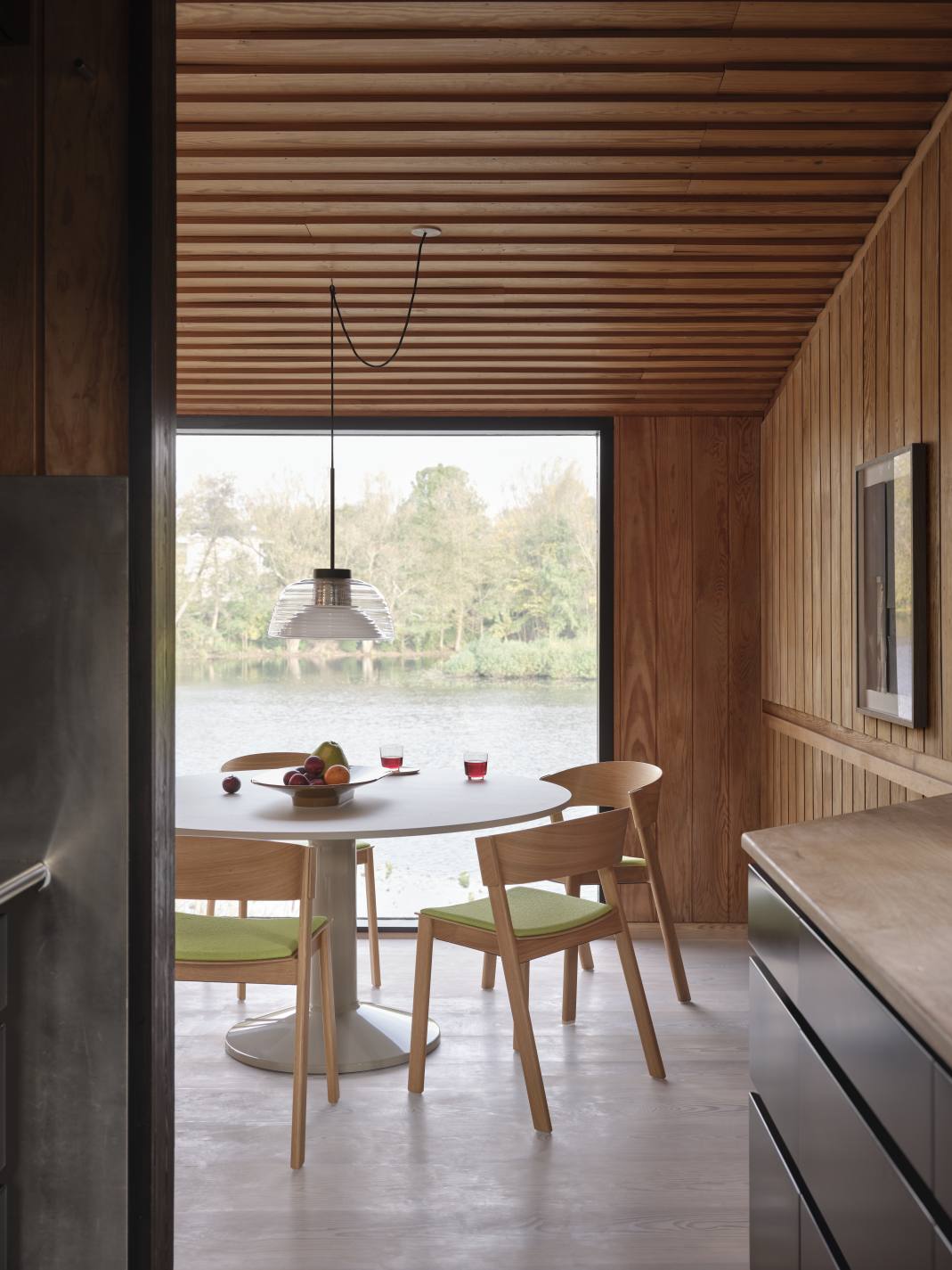 Heller Raum mit Muuto MIDST Table Esstisch, Stühlen, Obstschale und Blick auf einen See.