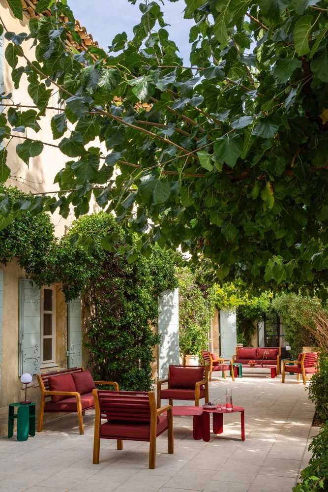 Fermob Somerset Sessel und Outdoor-Möbel in Rot und Holz auf einer Terrasse im Garten.