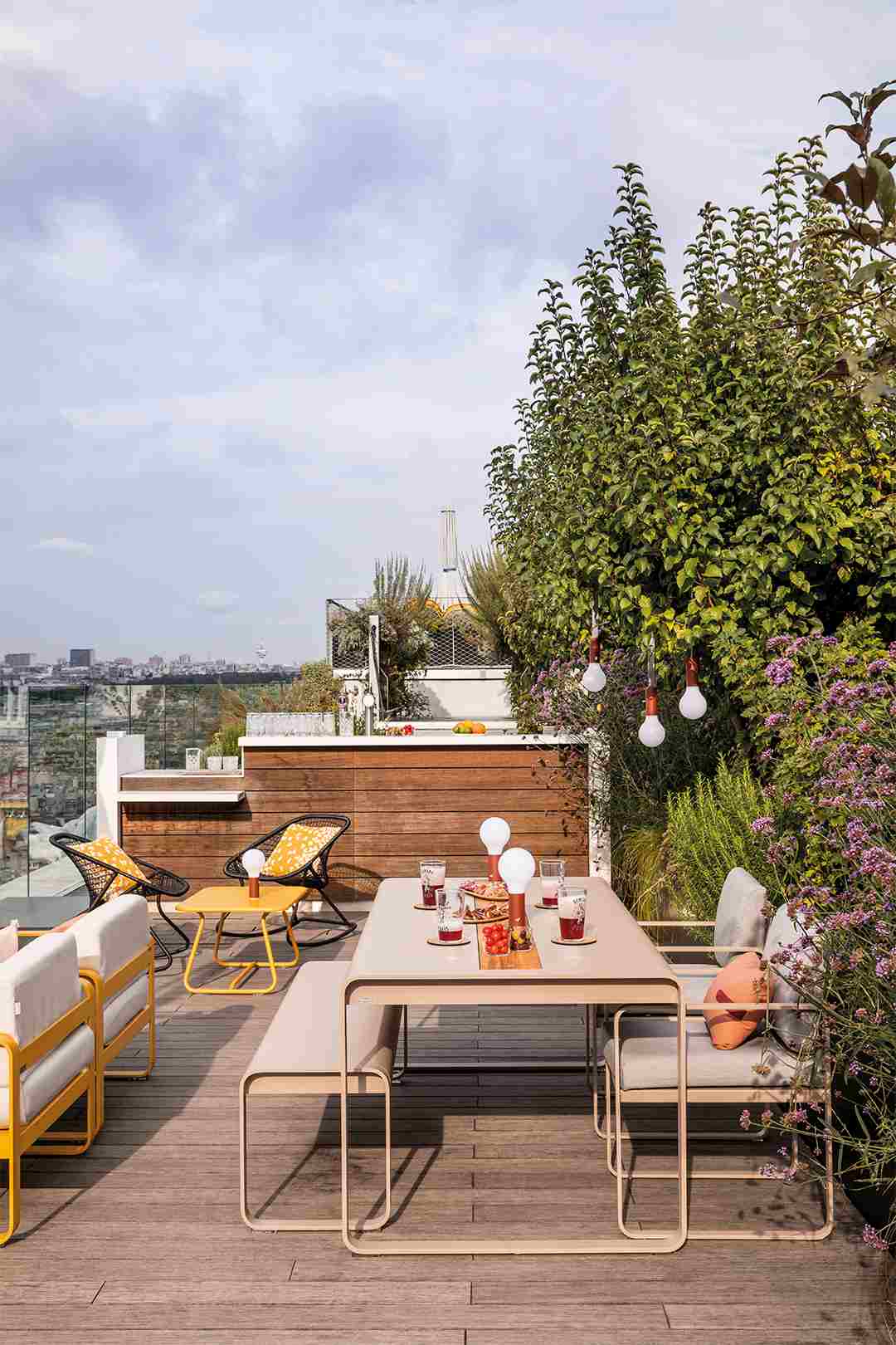 Bellevie Sessel von Fermob auf einer Dachterrasse mit Outdoor Möbeln und Blick auf die Stadt.