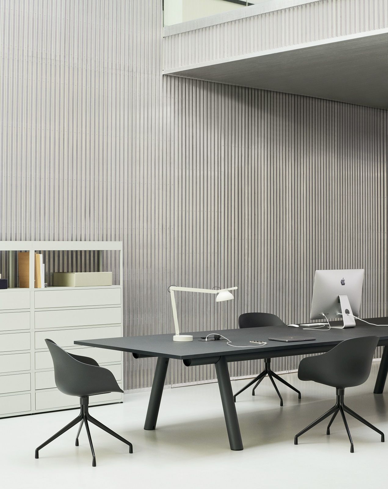 Büro mit schwarzem Tisch und drei grauen Hay About a Chair AAC220 Drehstühlen.