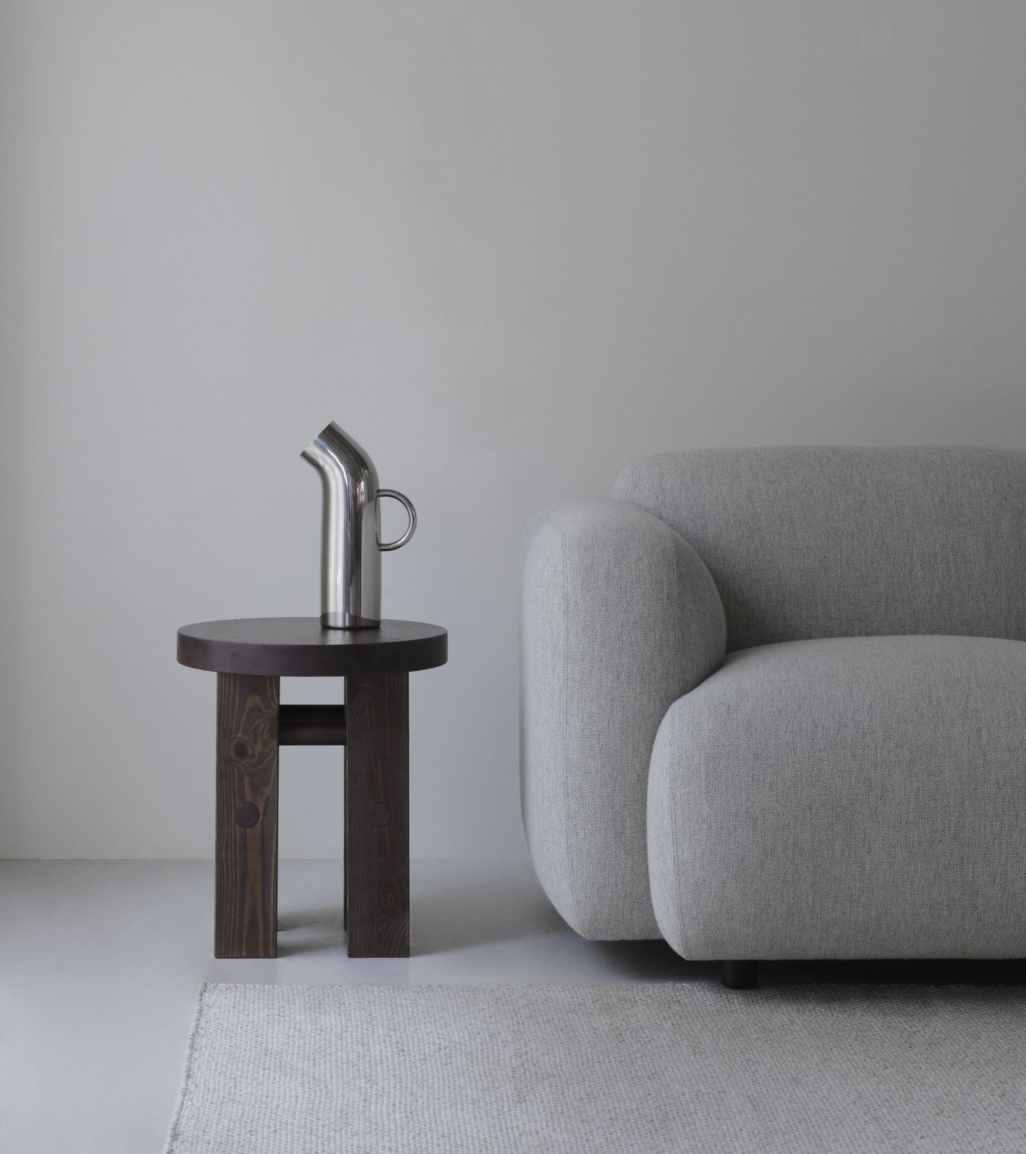 Fyr Stool Hocker von Normann Copenhagen aus dunklem Holz mit silberner Kanne aufgestellt.