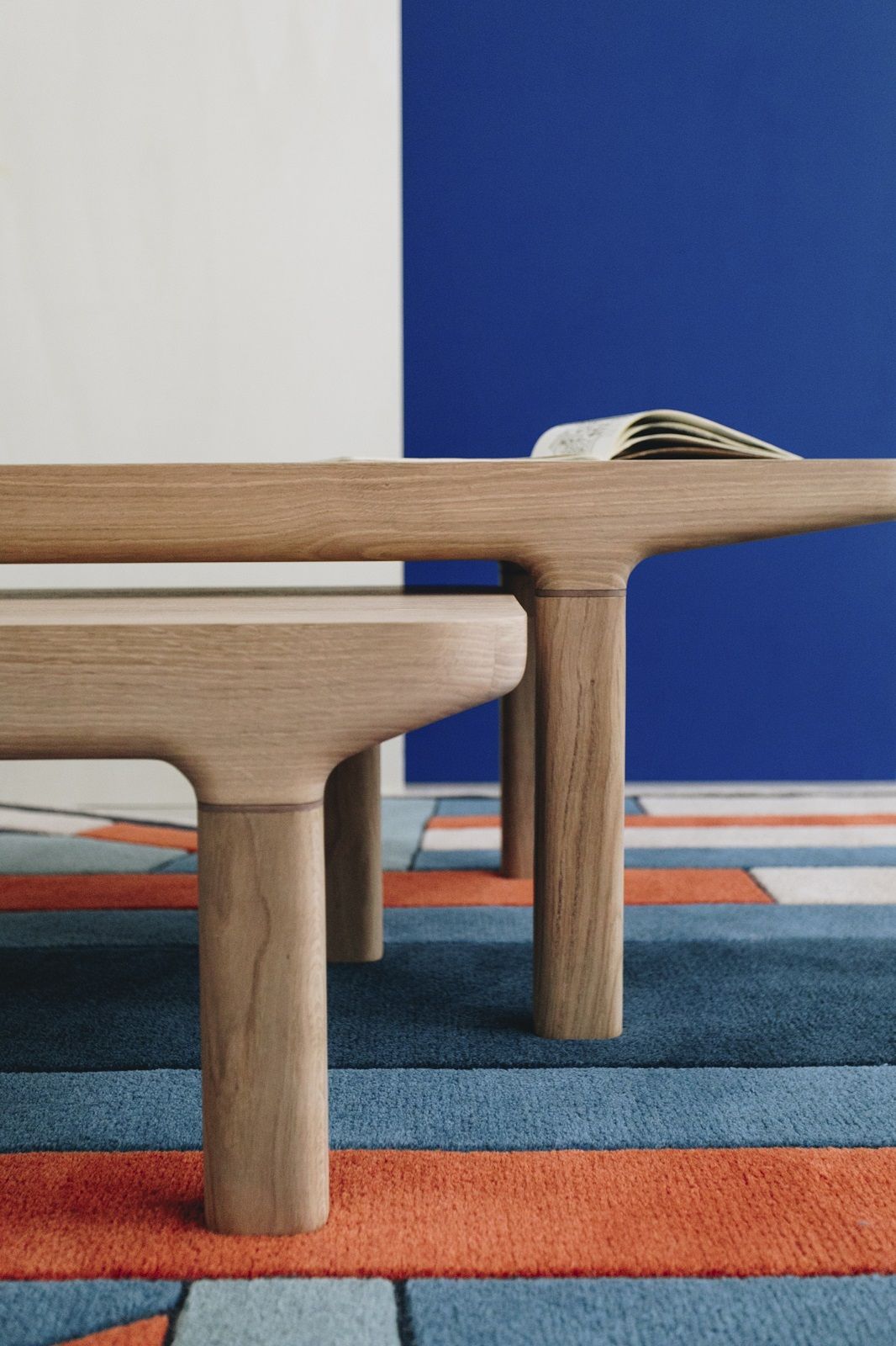 Detailaufnahme des Hartô Camille Couchtisches aus hellem Holz mit Buch, auf farbigem Teppich.