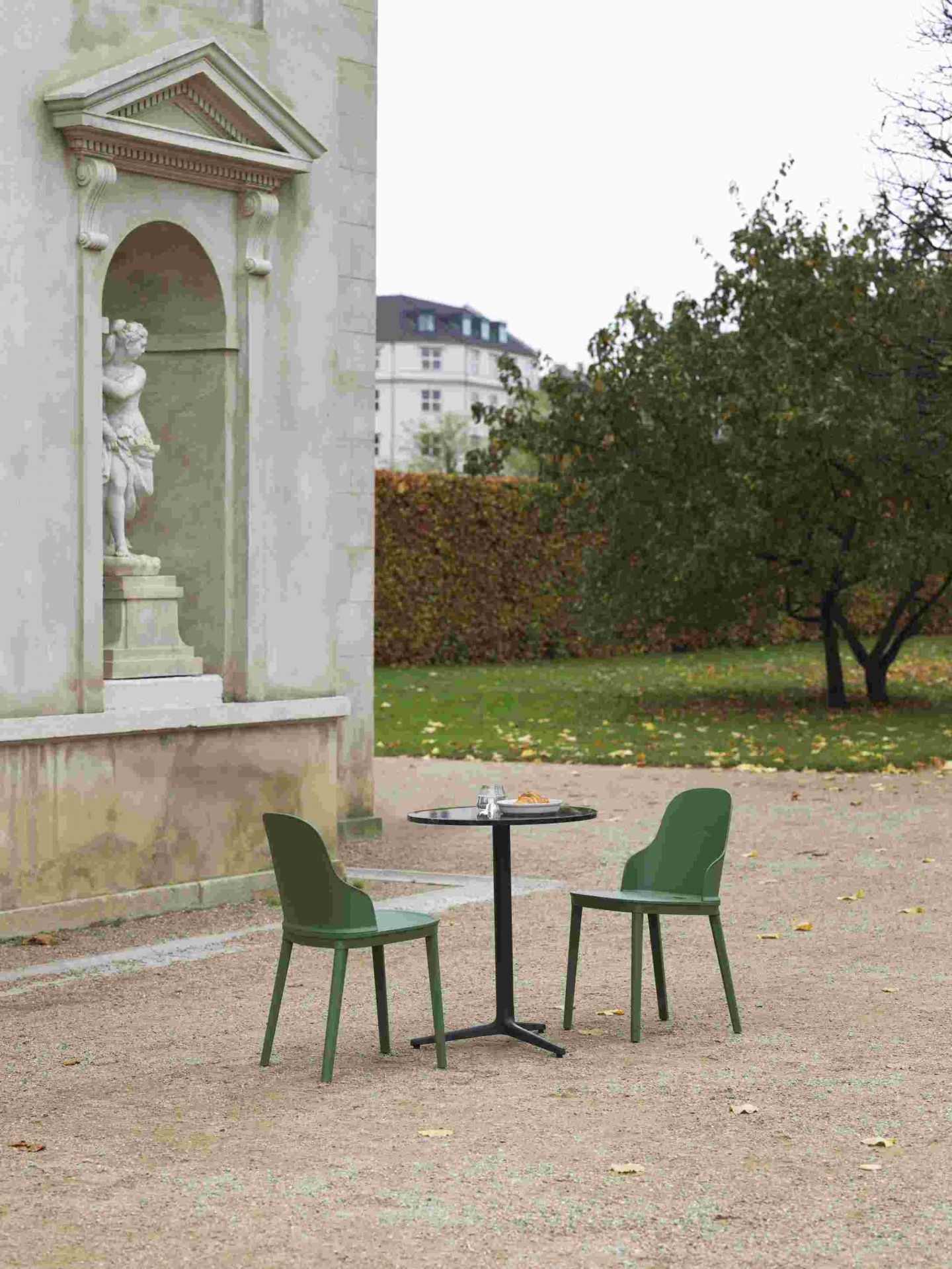 Zwei grüne Allez Chair Stühle von Normann Copenhagen mit Tisch im Außenbereich.