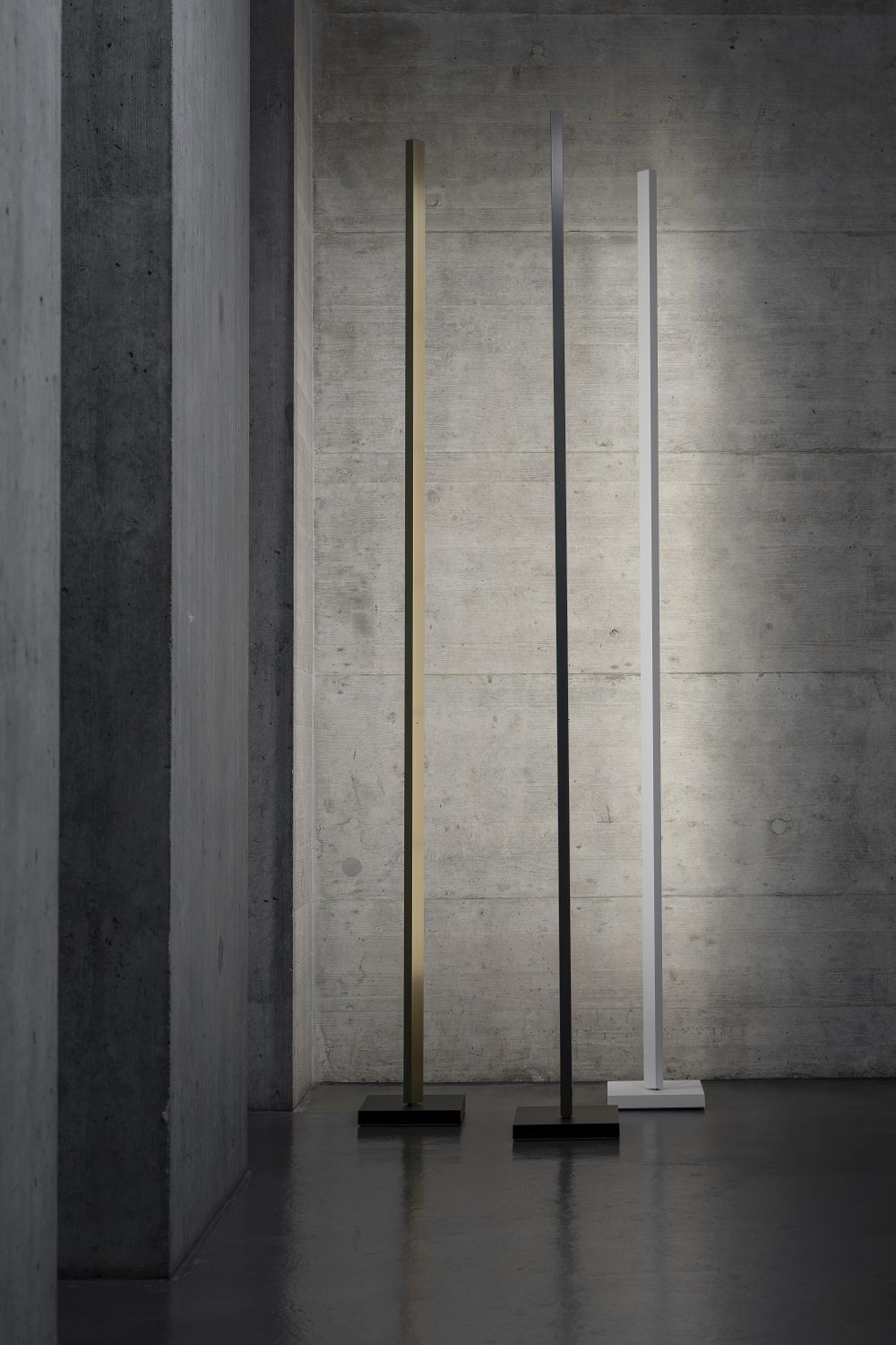 Zen Floor Lamp Stehleuchte in Gold, Schwarz und Weiß vor einer Betonwand.