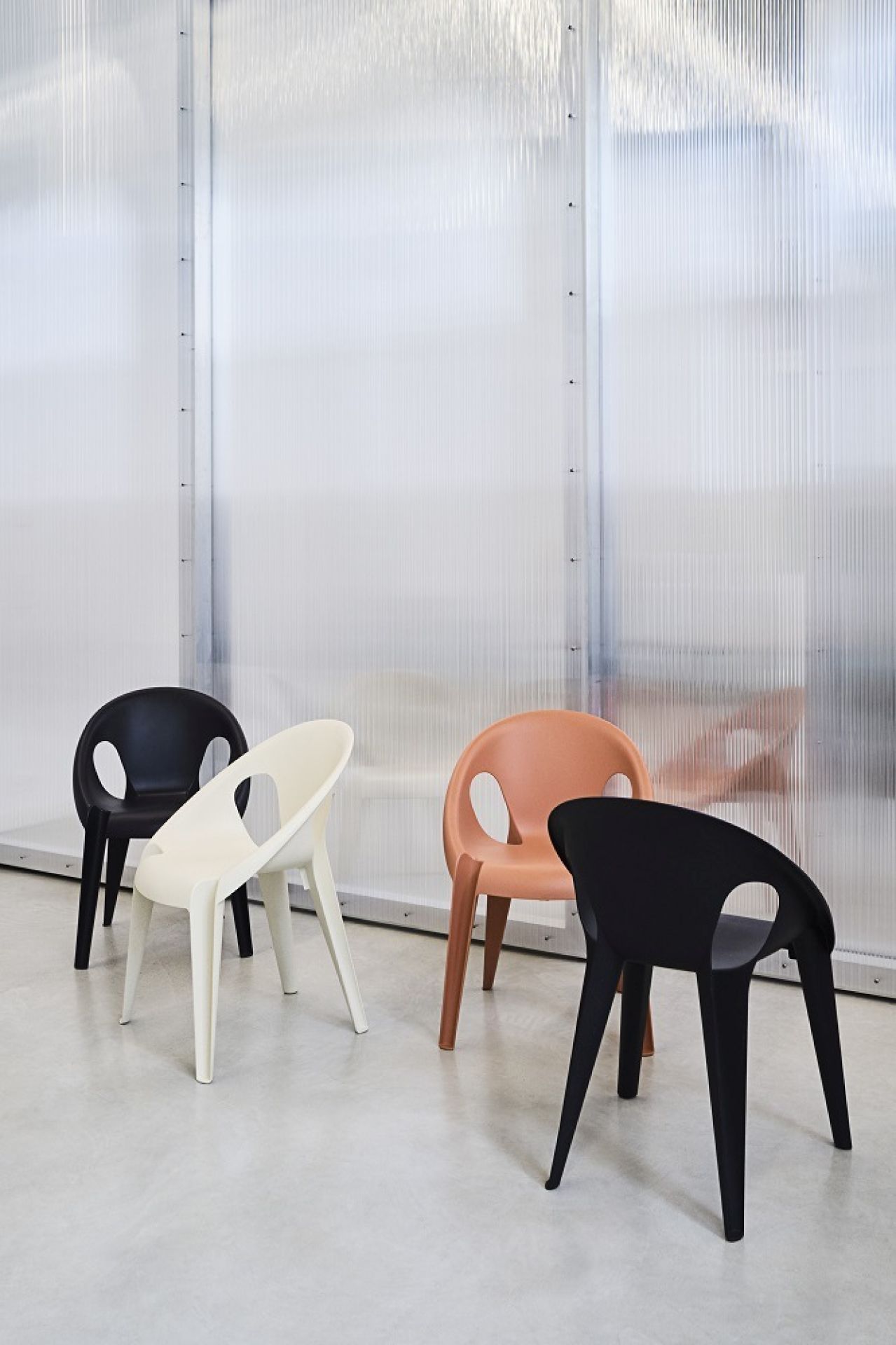 Vier Bell Stühle von Magis in Schwarz, Weiß und Orange. Stapelbare Indoor/Outdoor Stühle mit Armlehnen.