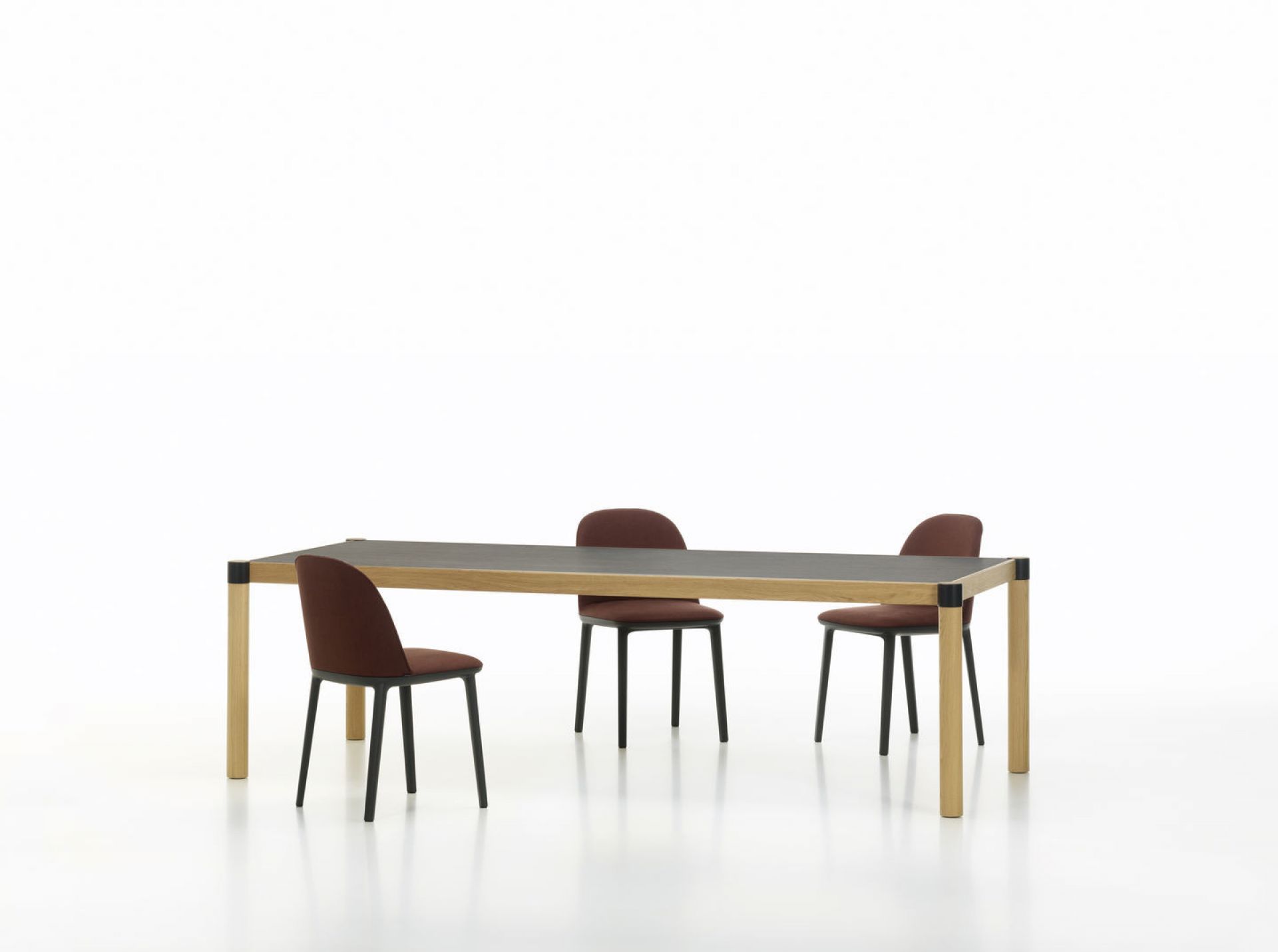 Vitra Softshell Side Chair Stühle in Rotbraun um einen Esstisch auf weißem Hintergrund.