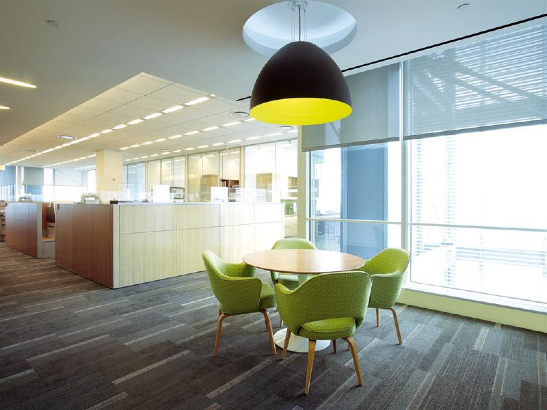 Saarinen Esstisch rund von Knoll International mit grünen Stühlen in modernem Büroambiente.