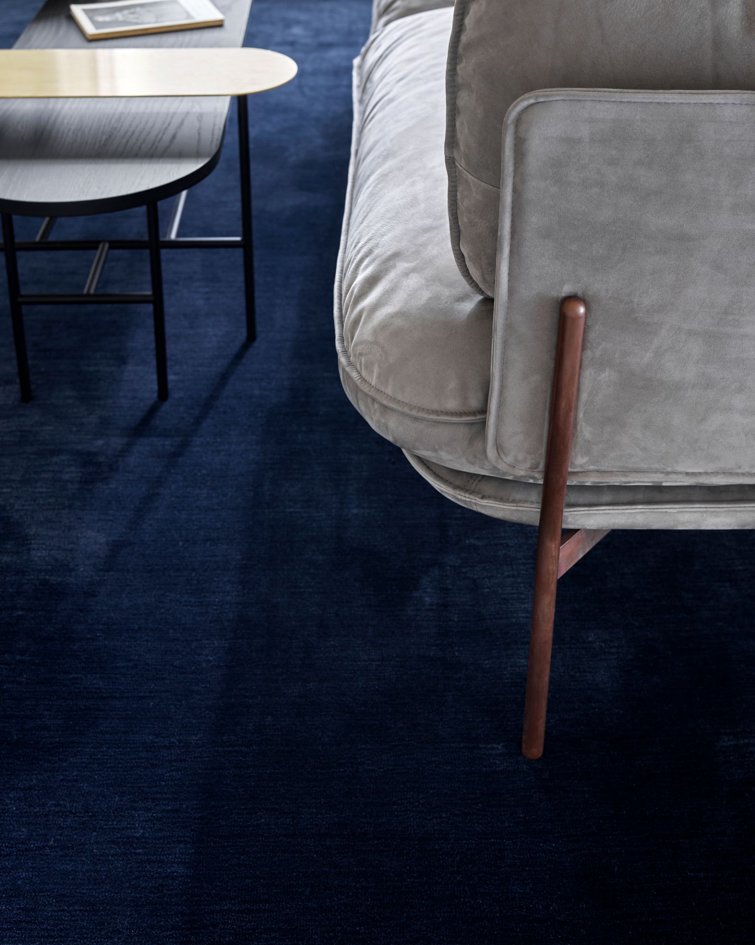 Detailaufnahme des Cloud Sofas von AndTradition, ein graues 3-Sitzer Sofa mit dunklem Teppich und Beistelltisch.