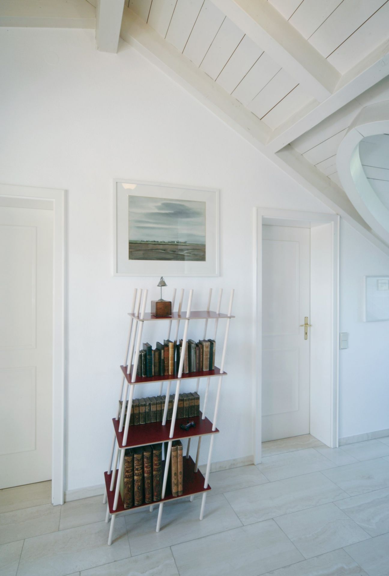 Nils Holger Moormann Regal mit Büchern in einem hellen Raum mit Dachschräge und weißen Wänden.
