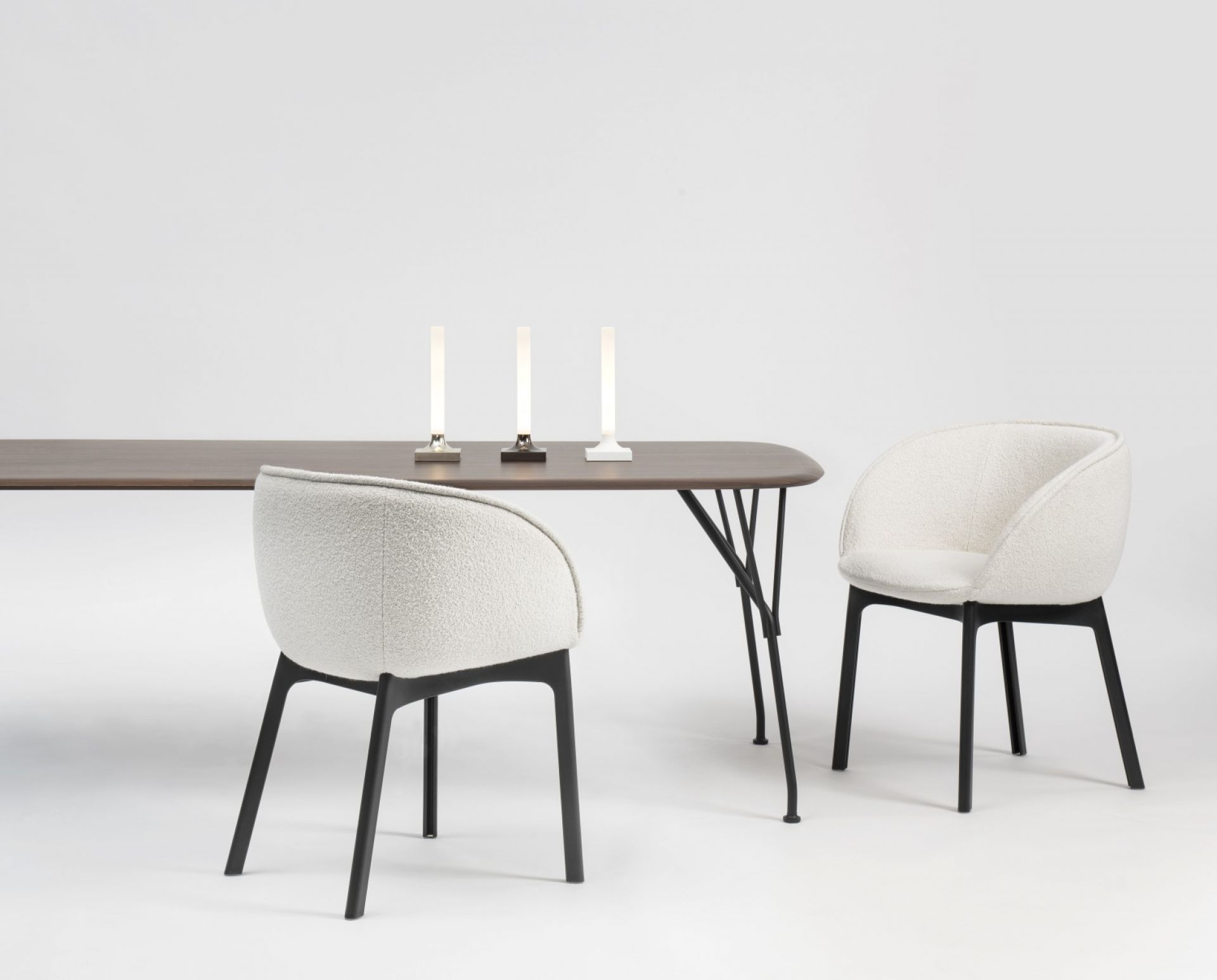 Tisch mit Stühlen und drei Goodnight Akkuleuchten von Kartell in verschiedenen Farben.