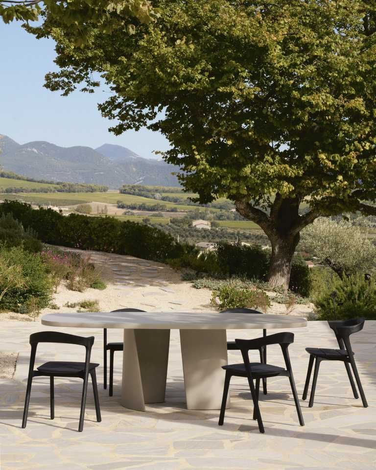 Canyon Outdoor Esstisch von Ethnicraft aus Beton mit Stühlen im Garten, Landschaft im Hintergrund.