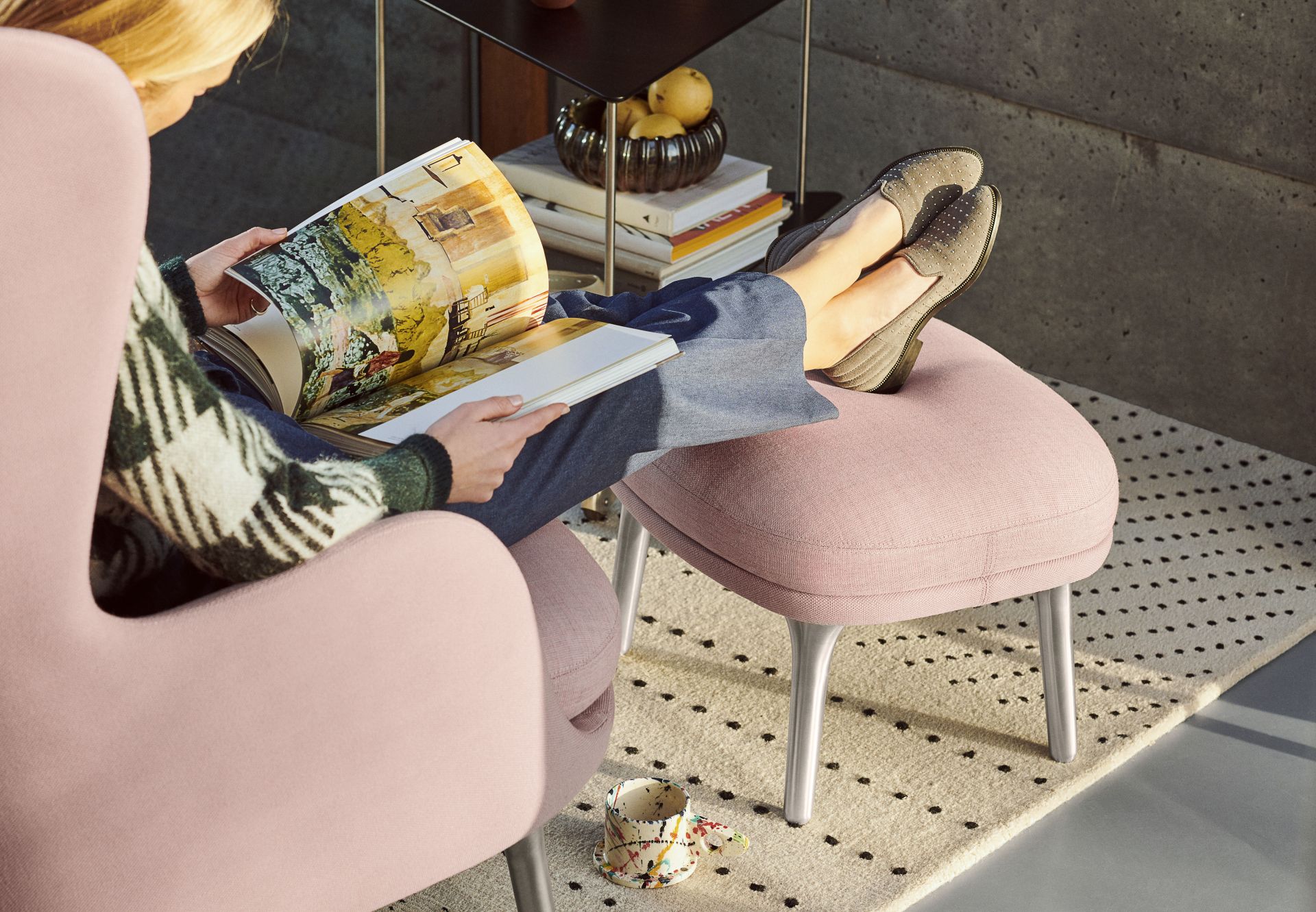 Frau liest entspannt im Ro Sessel von Fritz Hansen mit passendem Hocker in Rosa.