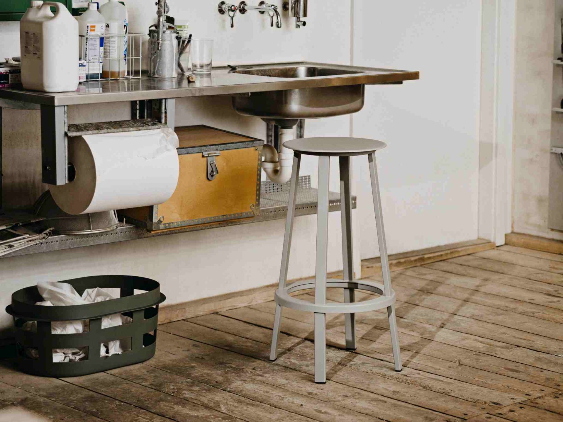 Grauer Revolver Bar Stool Barhocker von Hay vor einer Werkbank mit Spüle und Holzboden.