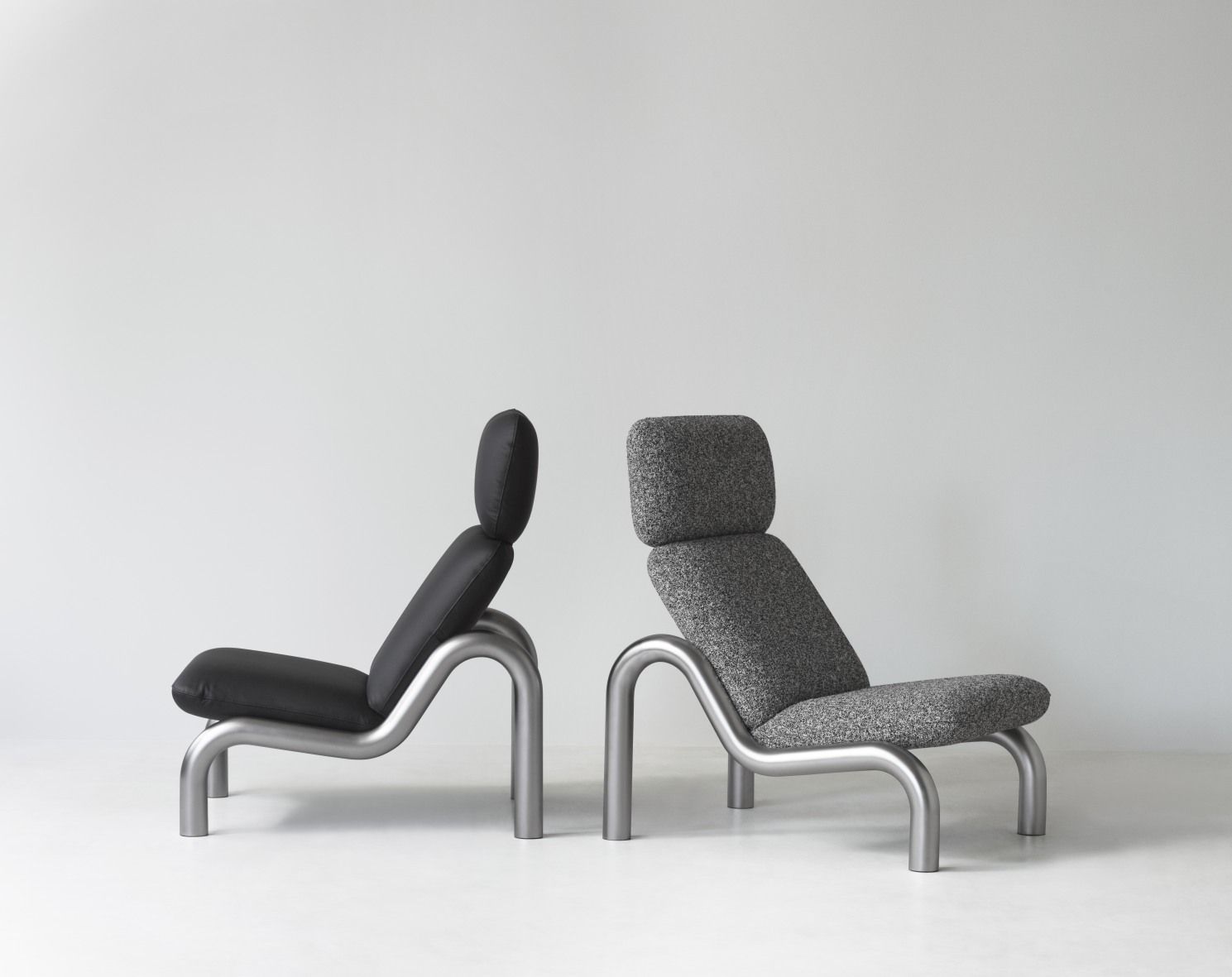 Zwei Tube Lounge Sessel von Normann Copenhagen, einer in Schwarzleder, einer in grauem Stoff.