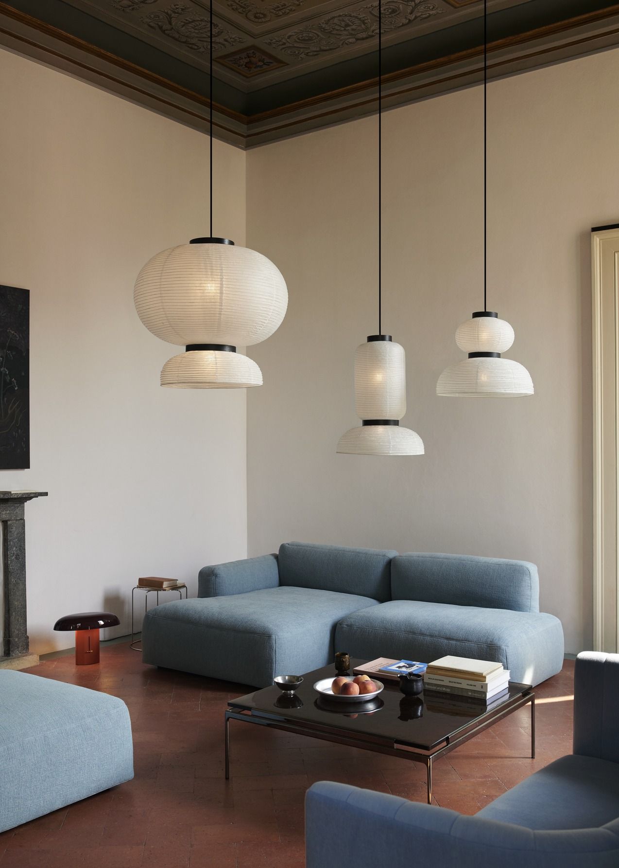 AndTradition Sett LN12 Couchtisch im Wohnzimmer mit blauer Couch und japanischen Papierleuchten.