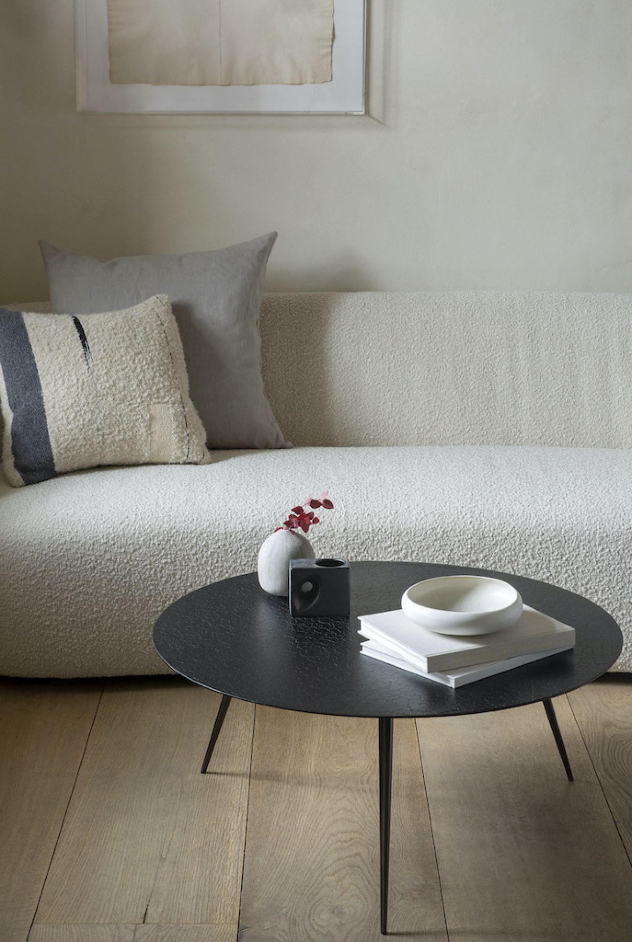 Luna Couchtisch: Runder, schwarzer Wohnzimmertisch mit Deko-Elementen vor einem beigen Sofa.