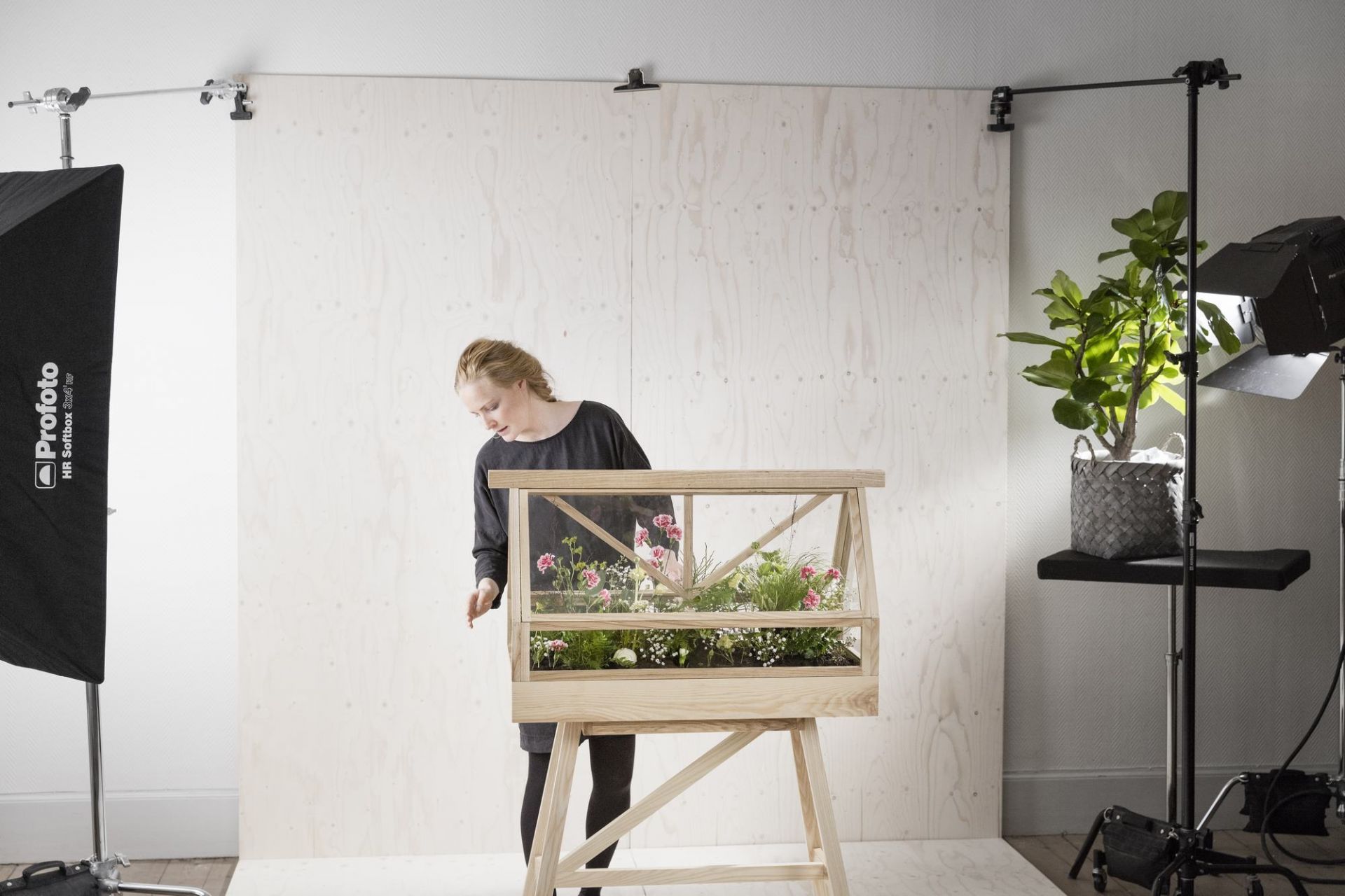 Frau betrachtet Greenhouse Gewächshaus von Design House Stockholm mit blühenden Pflanzen.