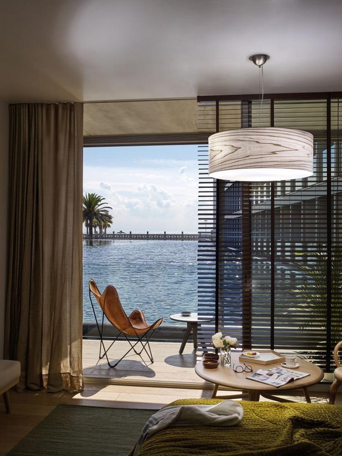 Gea LED Pendelleuchte von LZF Lamps über einem stilvollen Wohnraum mit Meerblick. Moderne Beleuchtung.