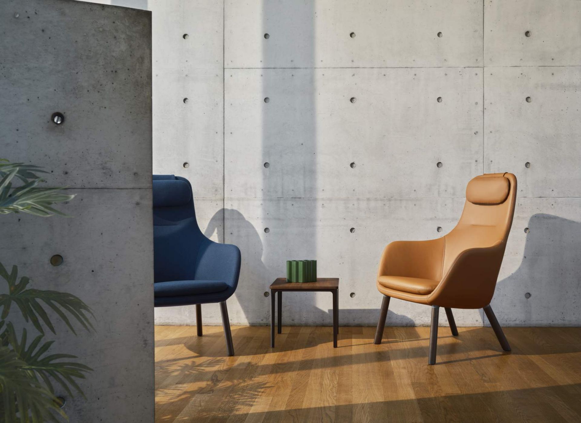 Vitra Hal Lounge Chair Sessel in Blau und Braun mit losem Sitzkissen vor Betonwand.