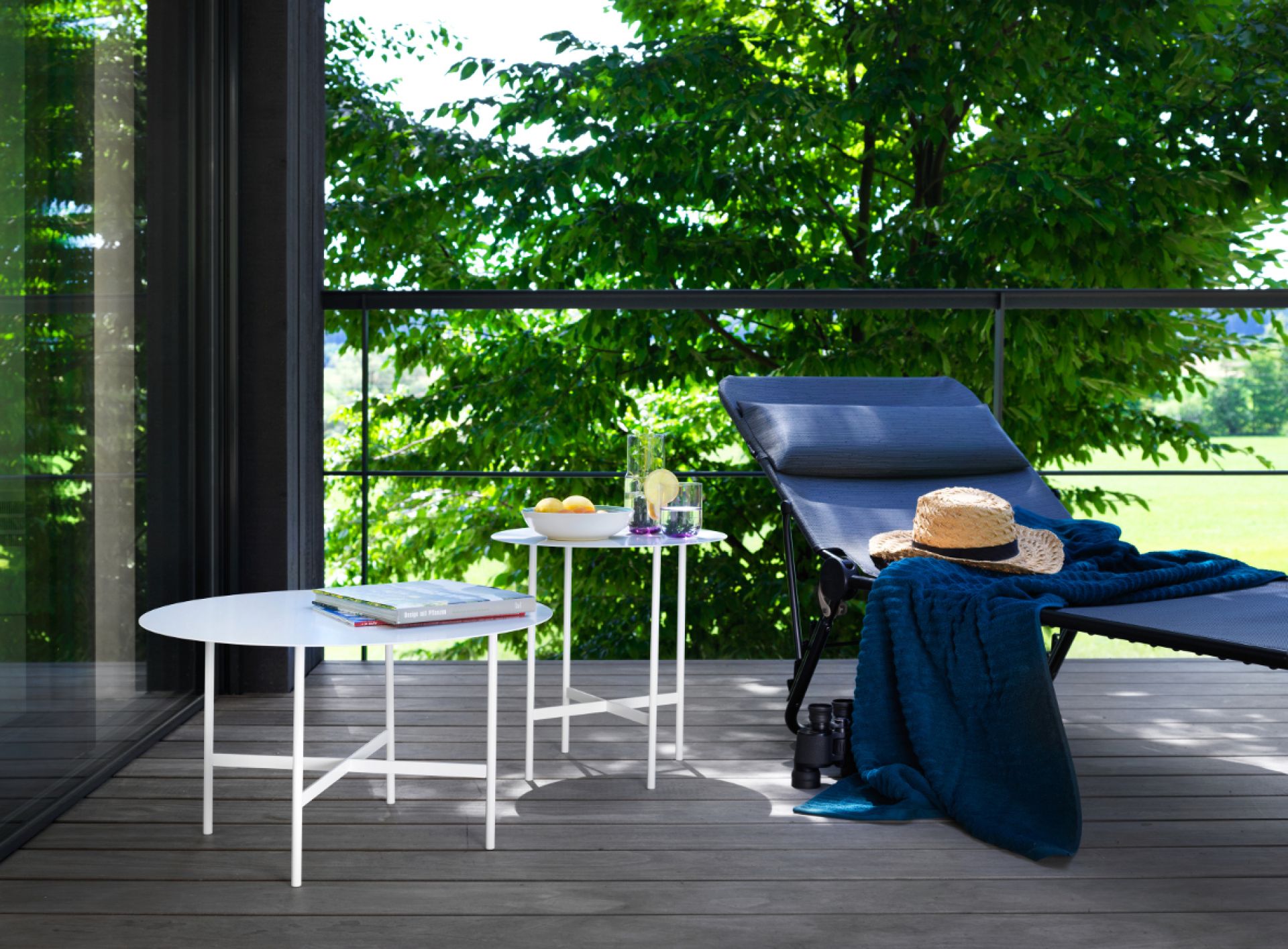 BETA Couchtisch und Beistelltisch von Müller Möbel auf einer Terrasse mit Liege und Ausblick.