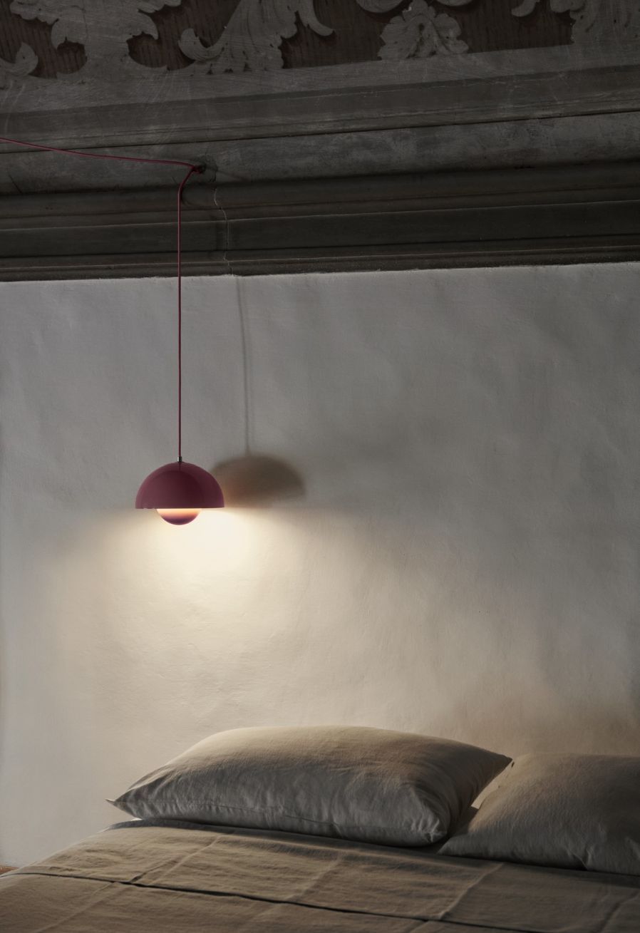 Nahaufnahme der rosafarbenen AndTradition Flowerpot Pendelleuchte über einem Bett, modernes skandinavisches Design.