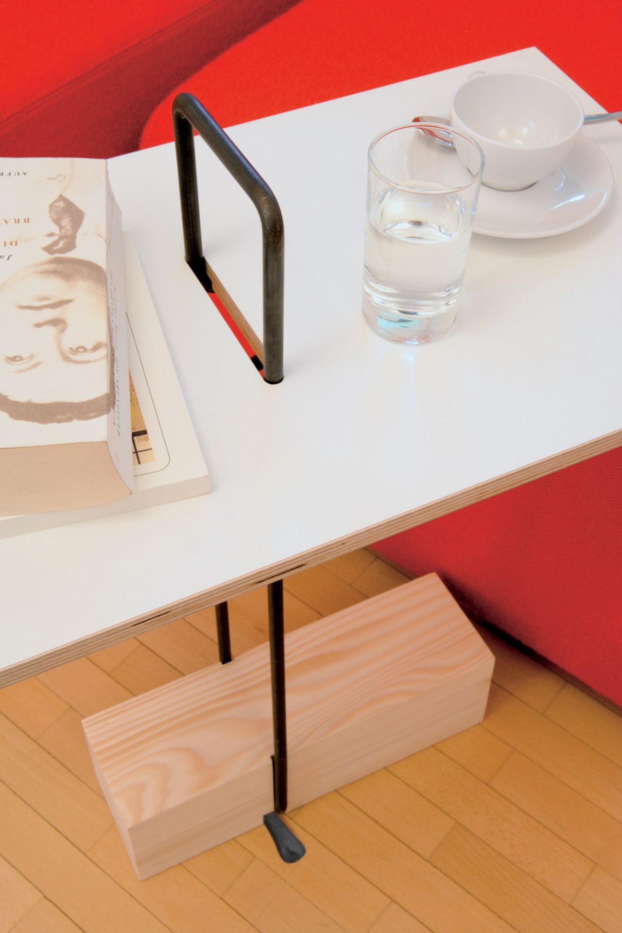 Abgemahnt Beistelltisch von Nils Holger Moormann mit Buch, Wasserglas und Kaffeetasse auf weißer Tischplatte.