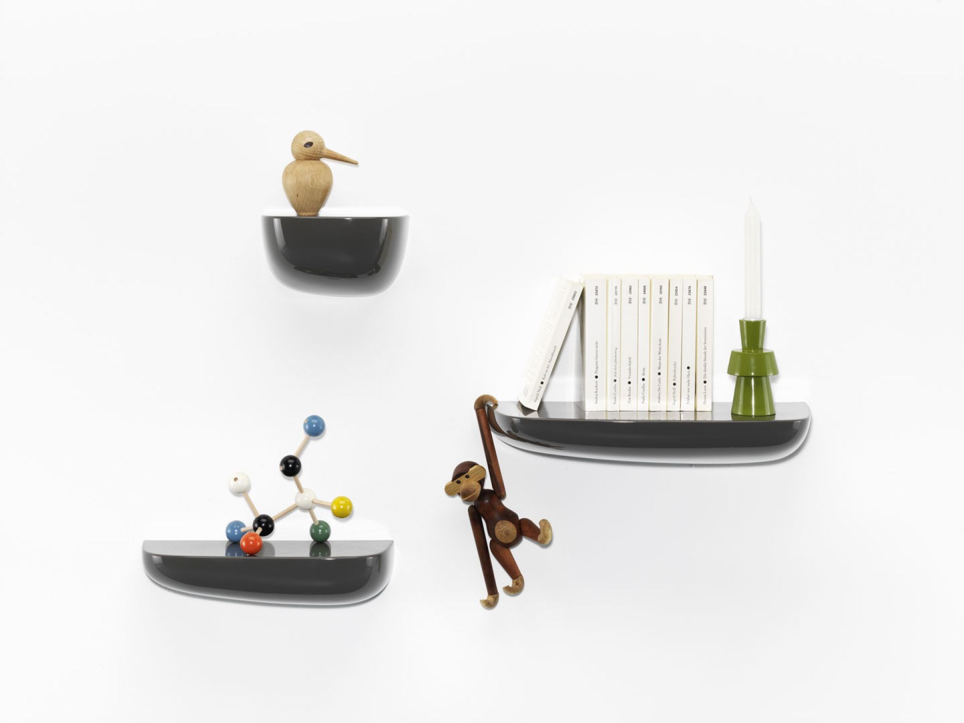 Drei graue Vitra Corniches Wandboards in verschiedenen Größen an einer weißen Wand mit Dekoration.