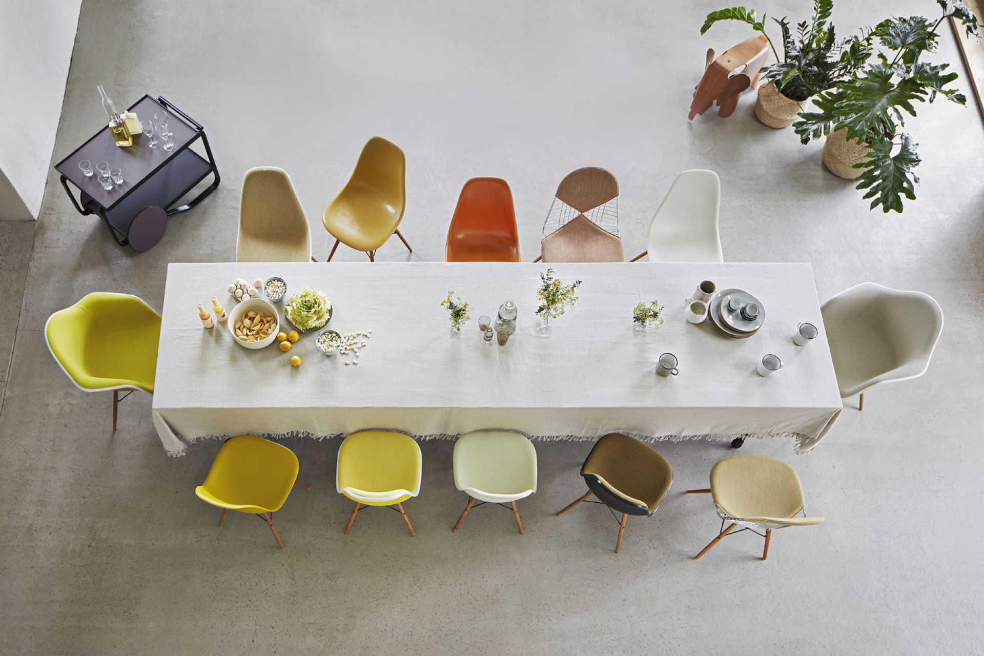 Esstisch mit verschiedenen Eames Plastic Chairs, darunter der schwarze DAR Stuhl von Vitra, von oben fotografiert.