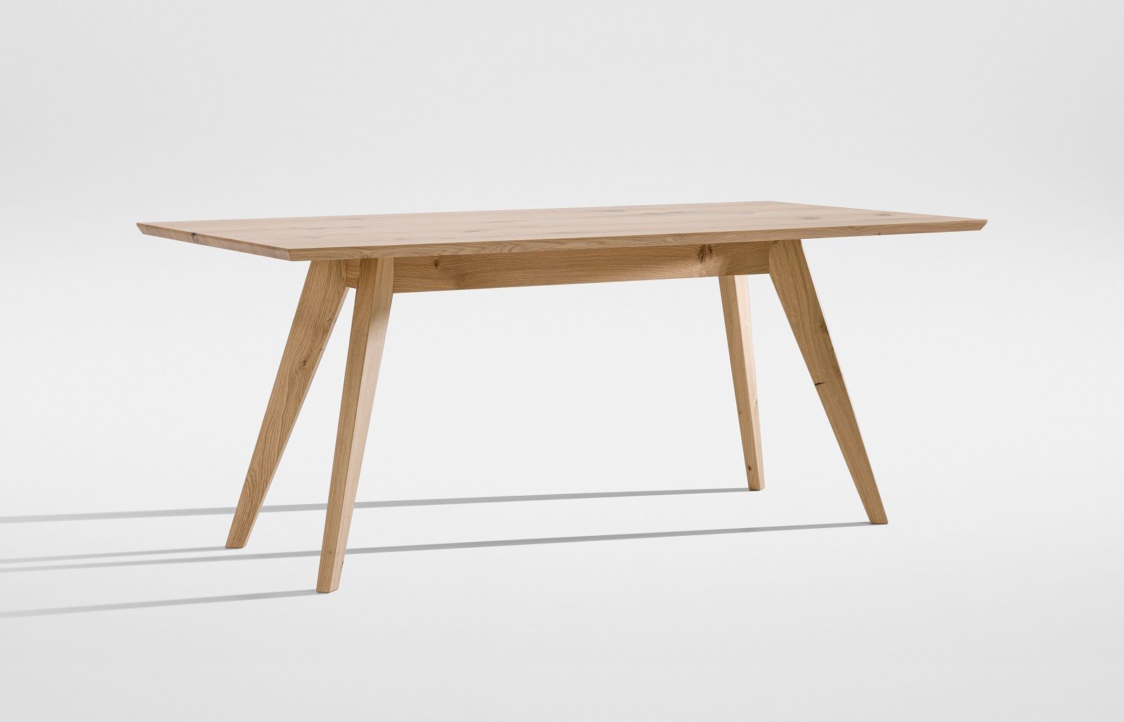 CENA Tisch, ein rechteckiger Esstisch aus hellem Holz mit schrägen Beinen, freigestellt auf weißem Hintergrund.
