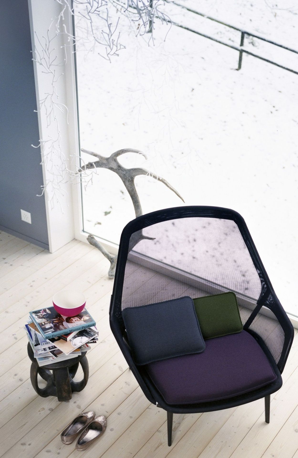Vitra Slow Chair Sessel mit Kissen in modernem Wohnzimmer mit Blick auf verschneite Landschaft.