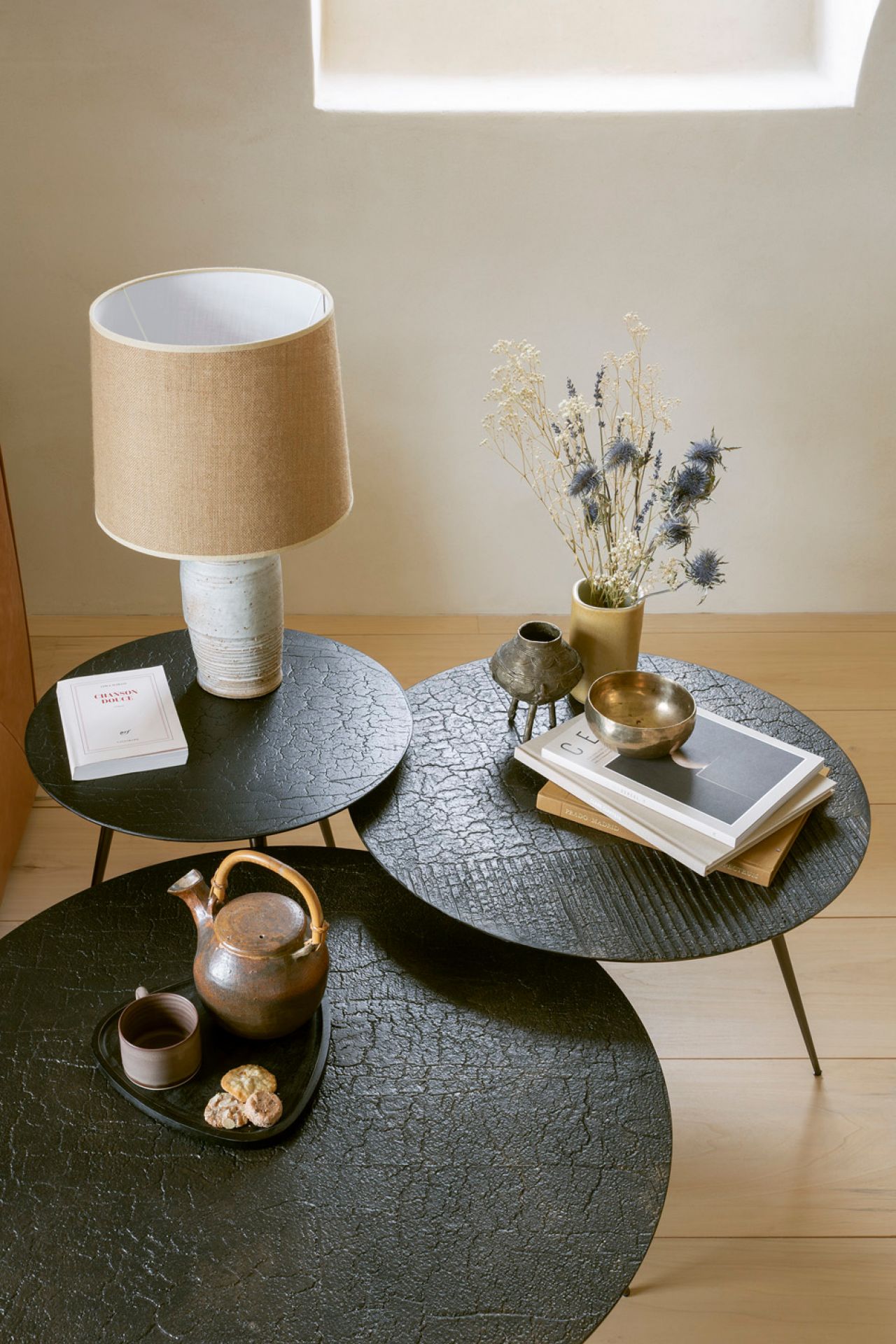 Luna Couchtisch Lava Linear Ethnicraft, drei runde Tische in Schwarz mit Teekanne, Lampe und Dekoration.