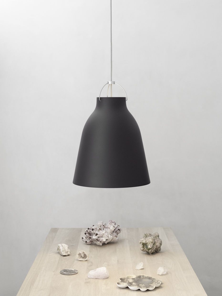 Schwarze Caravaggio Pendelleuchte von Fritz Hansen über einem Tisch mit Dekosteinen und Muscheln.