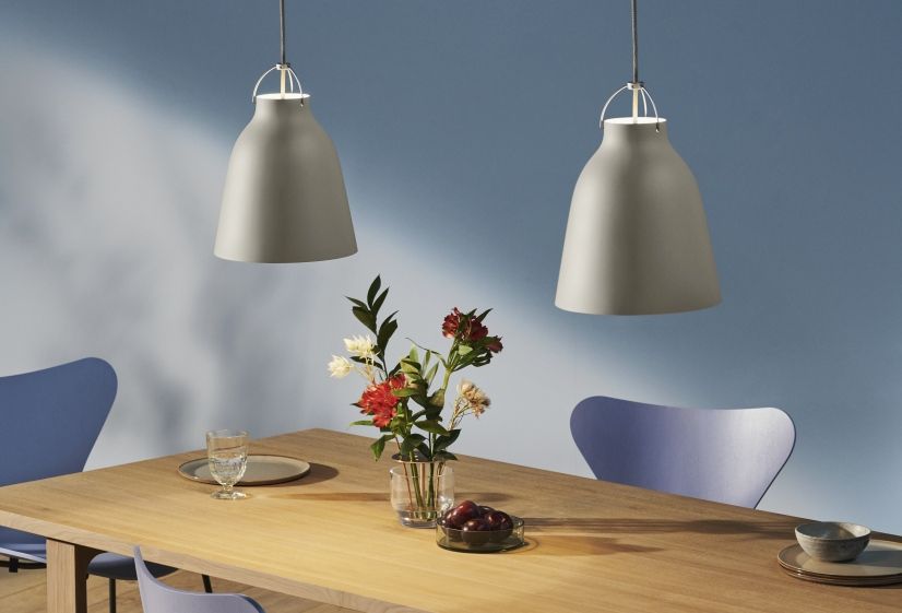 Zwei graue Caravaggio Pendelleuchten von Fritz Hansen über einem Esstisch mit Blumen und Geschirr.