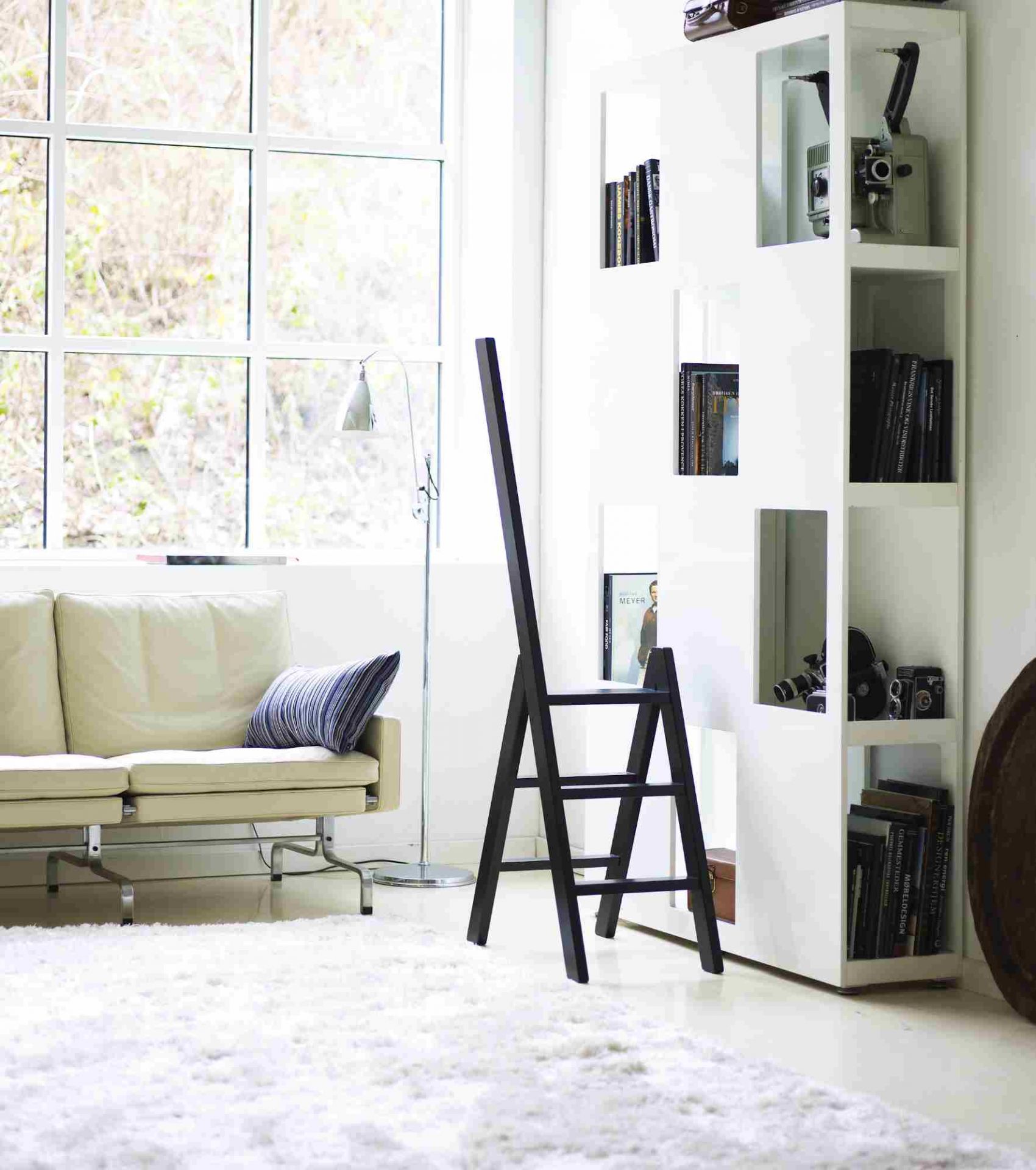 Schwarze Hindevadgaard Trittleiter aus Holz im modernen Wohnzimmer mit Sofa, Regal und Fenster.