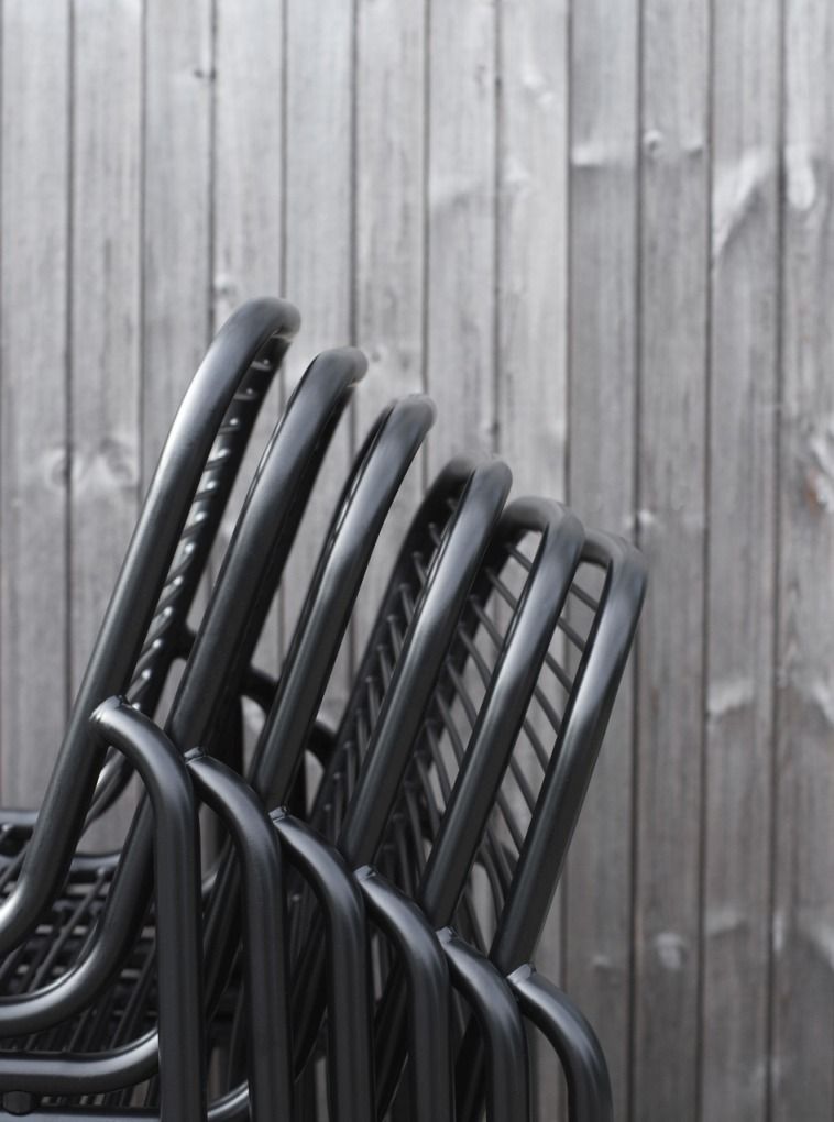 Detailaufnahme von gestapelten, schwarzen Vig Chair Stühlen von Normann Copenhagen für den Außenbereich.