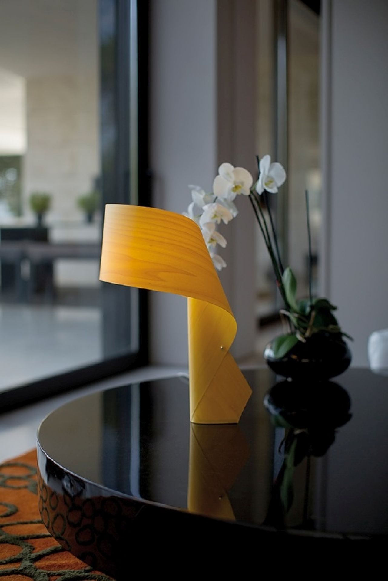 Air Table Tischleuchte von LZF Lamps: Moderne, graue Designerleuchte aus Holzfurnier auf einem schwarzen Tisch.