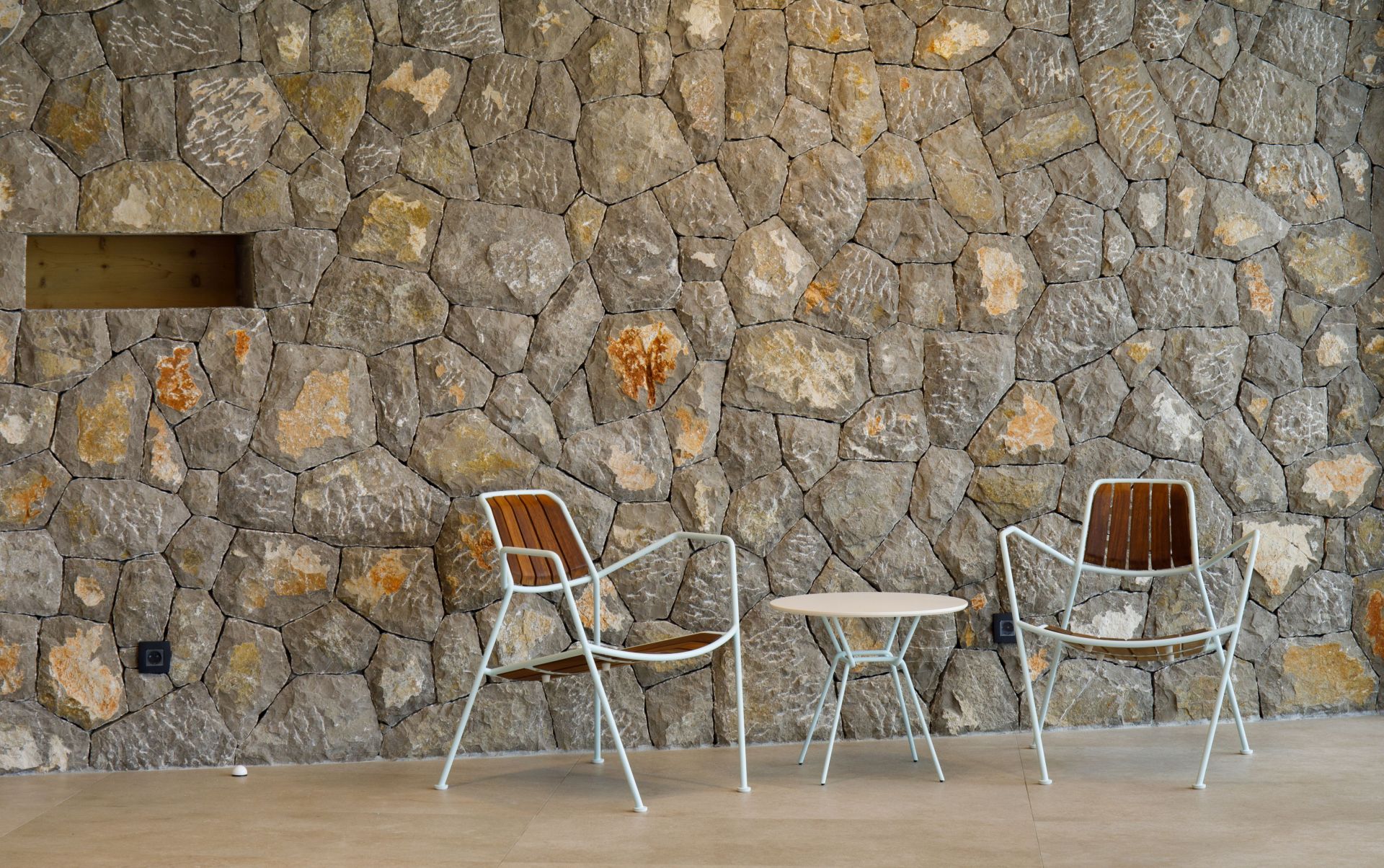 Zwei Osmo Outdoor Teak Stühle von Prostoria und ein Tisch vor einer Steinwand.