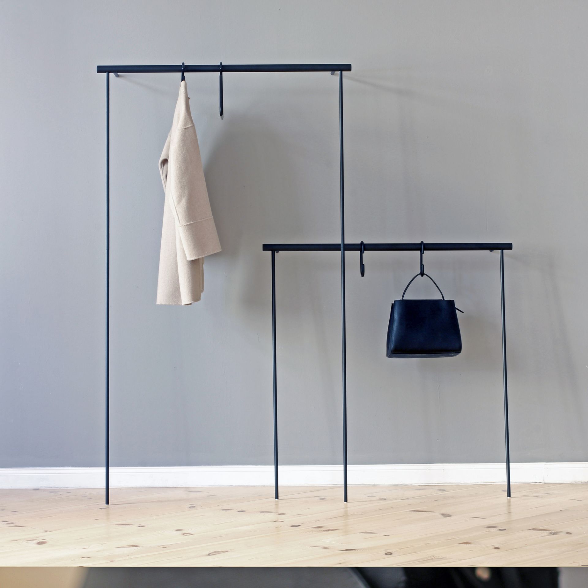Leanon II Anlehngarderobe von Roomsafari: Schwarze Säule mit Stangen, Mantel und Tasche.