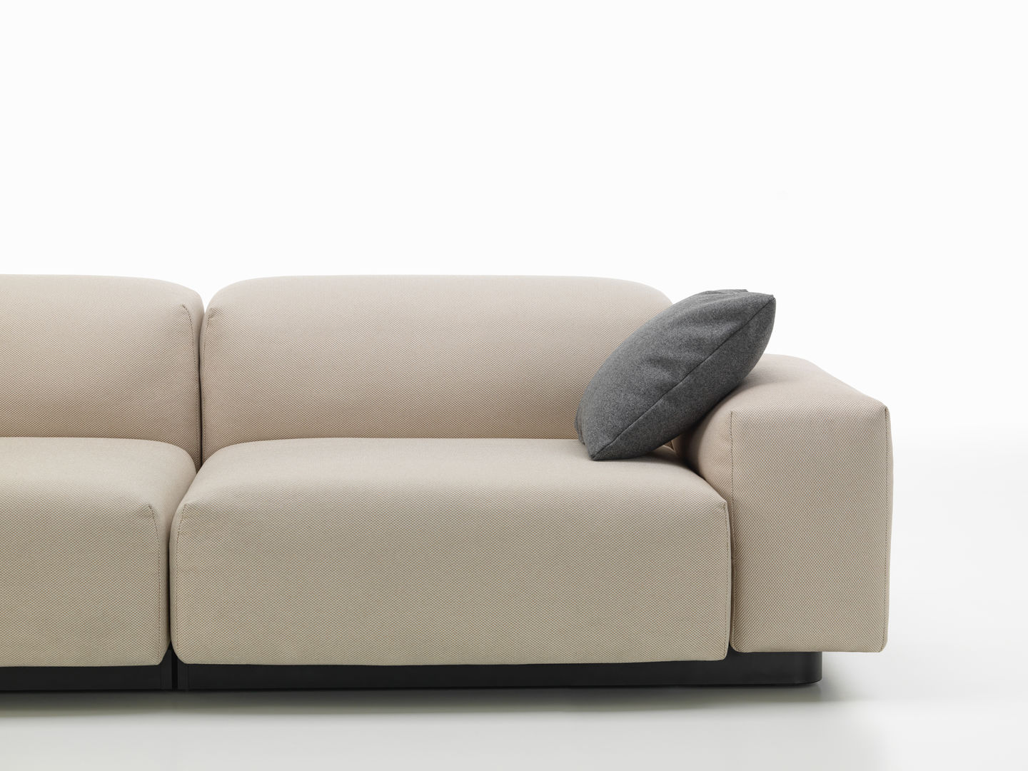 Beige Couch mit grauem Vitra Kissen / Sofakissen als Dekoration, modernes Wohnzimmer-Design.