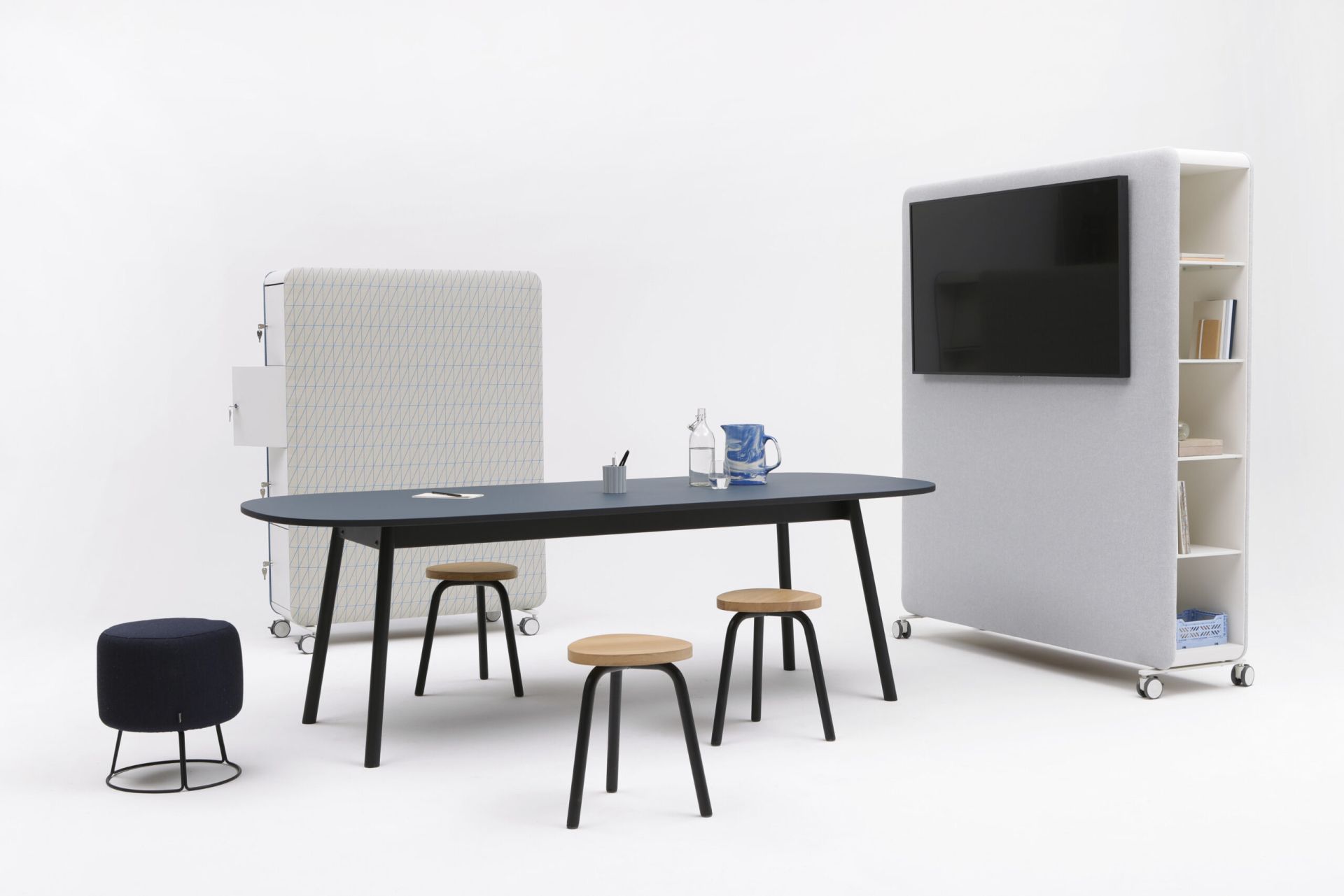 Cascando Pillow Space Akustik-Raumteiler mit Tisch, Stühlen und einem Raumteiler mit integriertem Bildschirm für moderne Büroräume.
