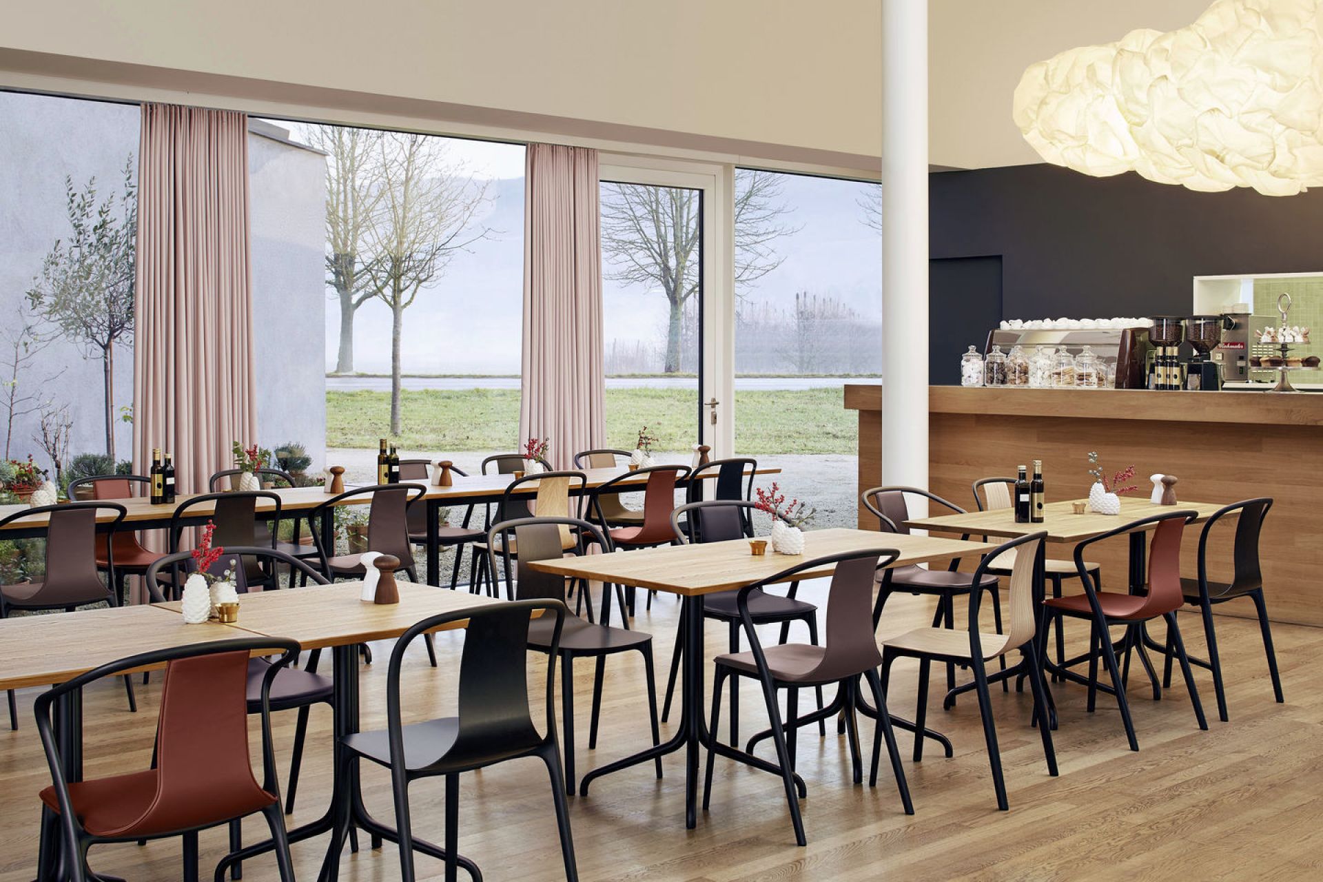 Innenaufnahme eines Restaurants mit Tischen und mehreren Vitra Belleville Chair Wood Stühlen in verschiedenen Farben.