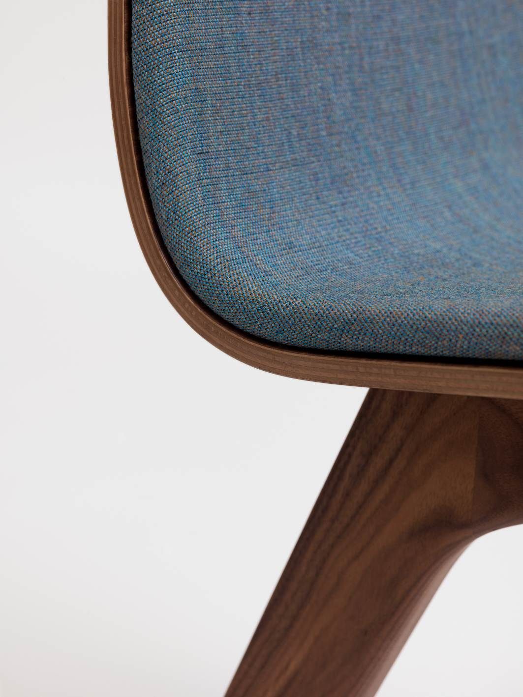 Detailaufnahme: Morph Holzstuhl mit blauem Sitzpolster und dunklem Holzgestell. Design Stuhl.