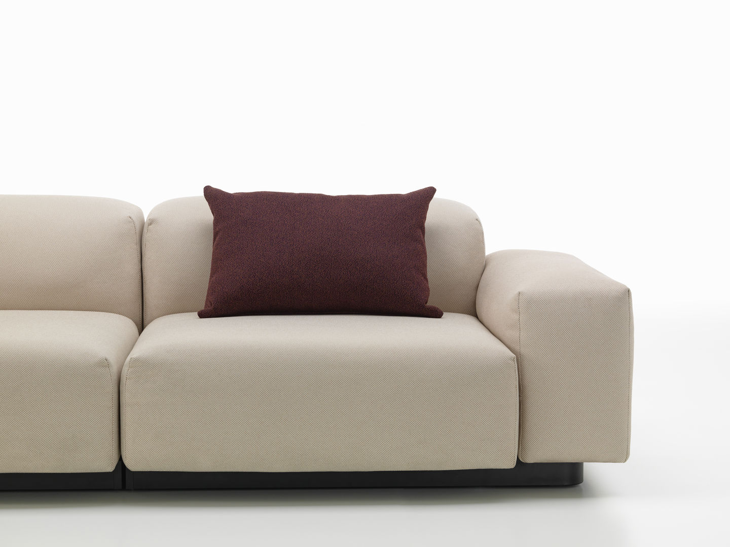 Vitra Kissen: Quadratisches Sofakissen in Aubergine auf einem beigen Stoffsofa, modernes Wohnaccessoire für stilvolles Interieur.
